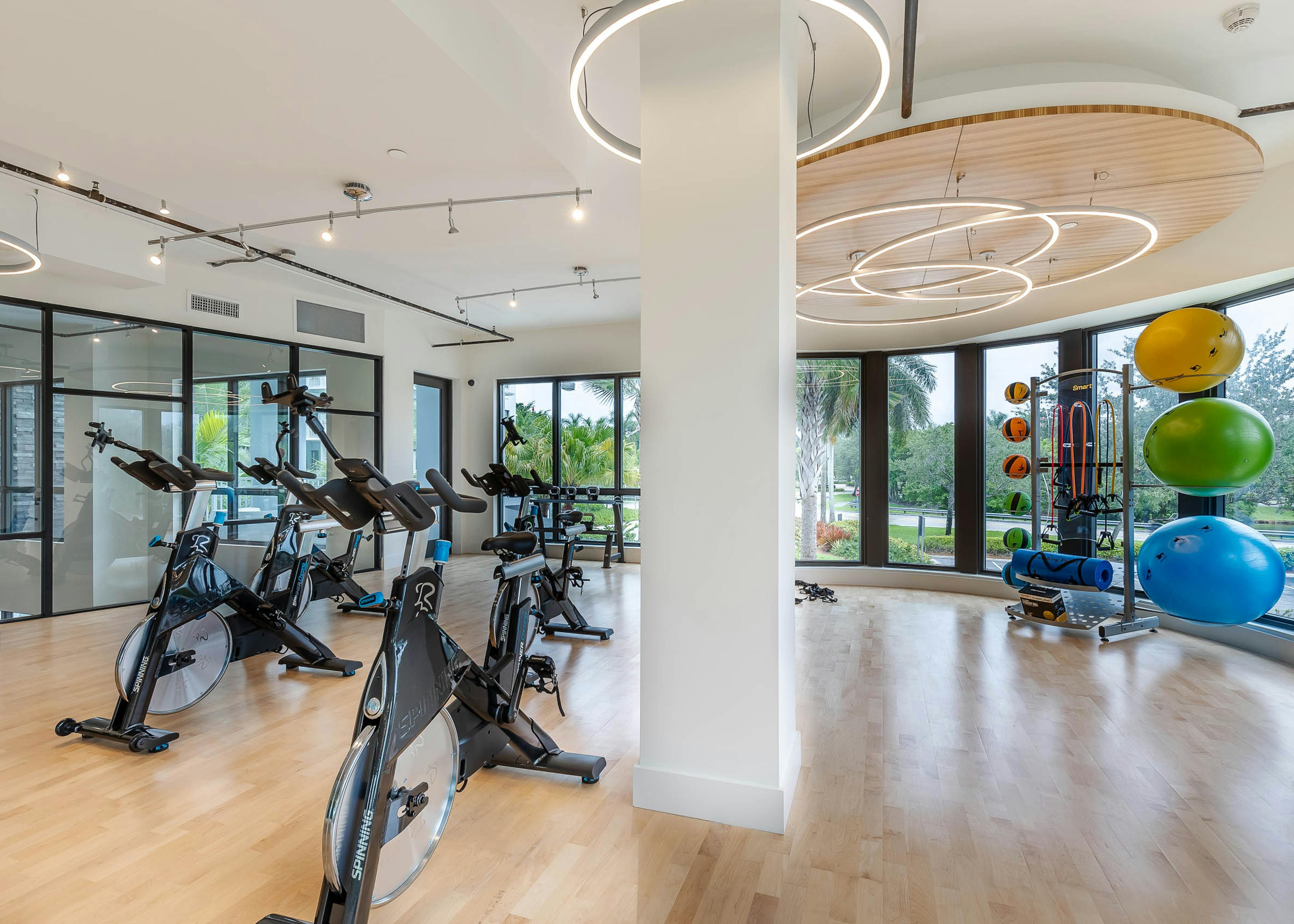 The AMLI Park West apartments yoga room with wood plank floors and spin bikes with exercise balls and circular lighting 