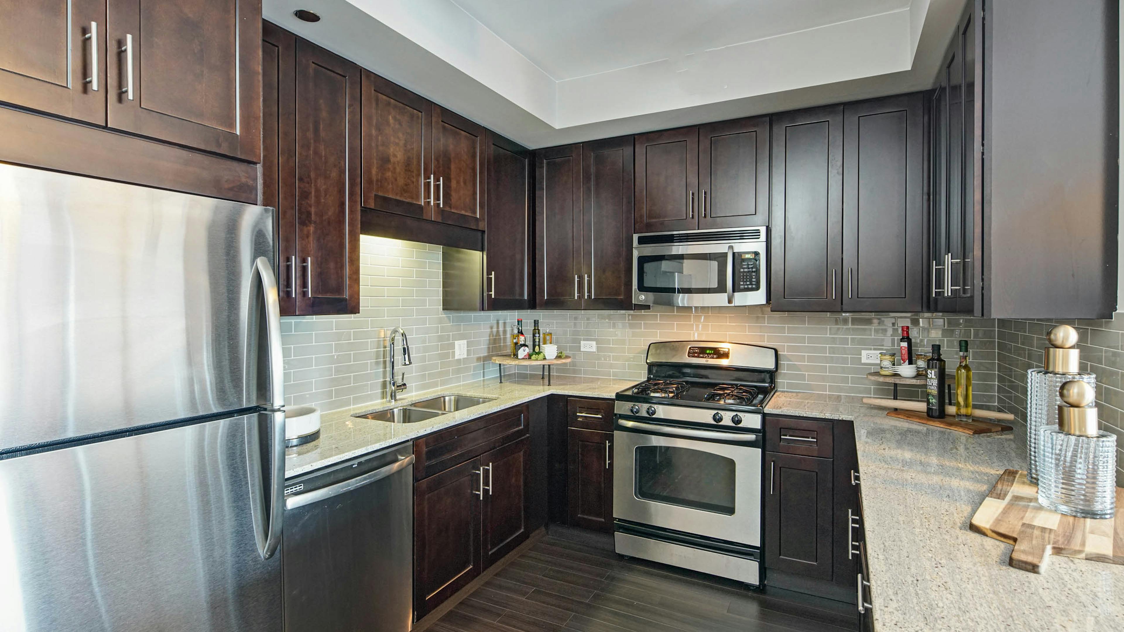 AMLI River North apartment kitchen with dark wood cabinets and granite countertops featuring stainless steel appliances