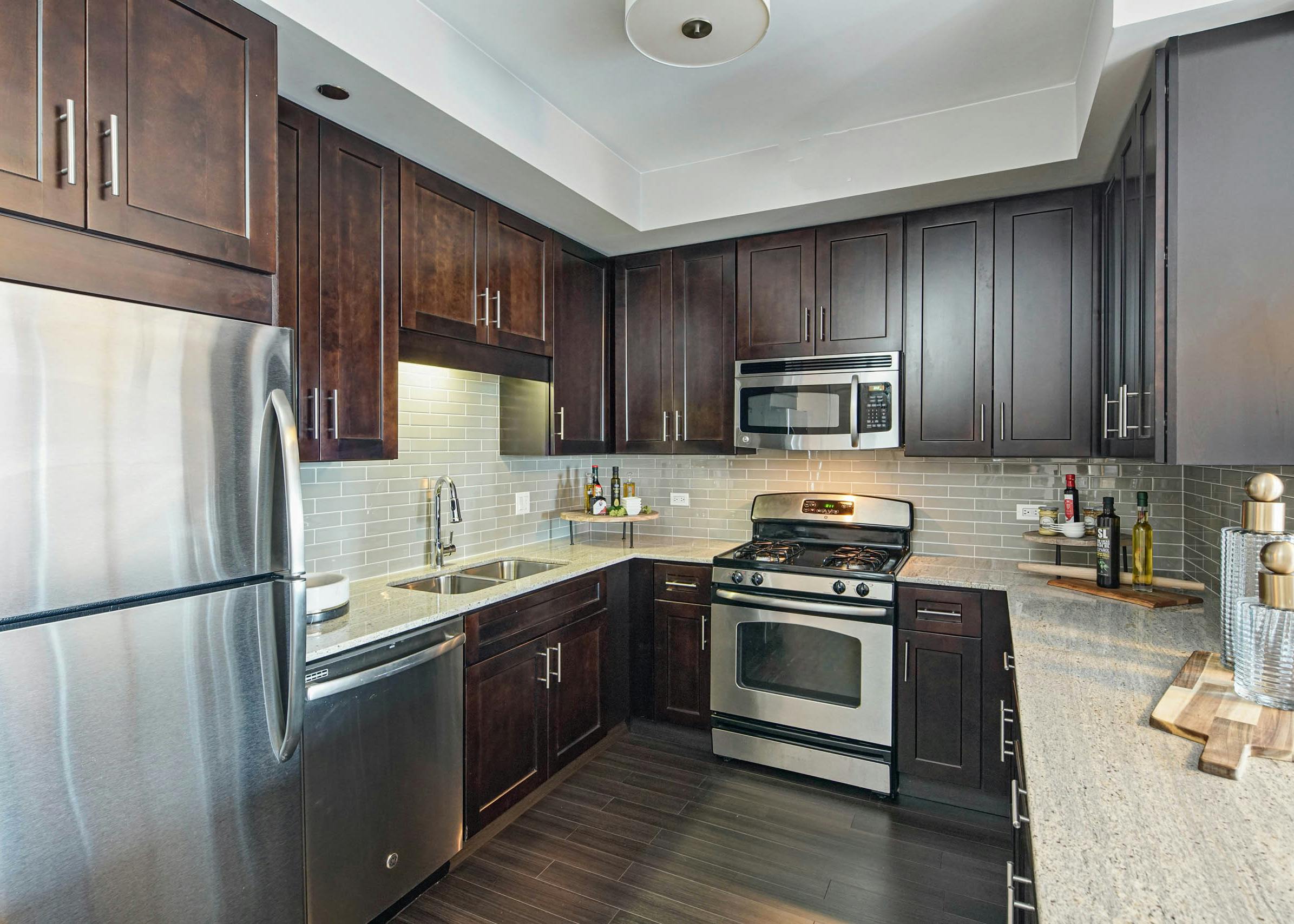 AMLI River North apartment kitchen with dark wood cabinets and granite countertops featuring stainless steel appliances