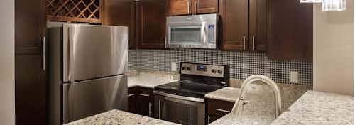Interior of AMLI Memorial Heights apartment kitchen with dark wood cabinets, tile backsplash and stainless steel appliances