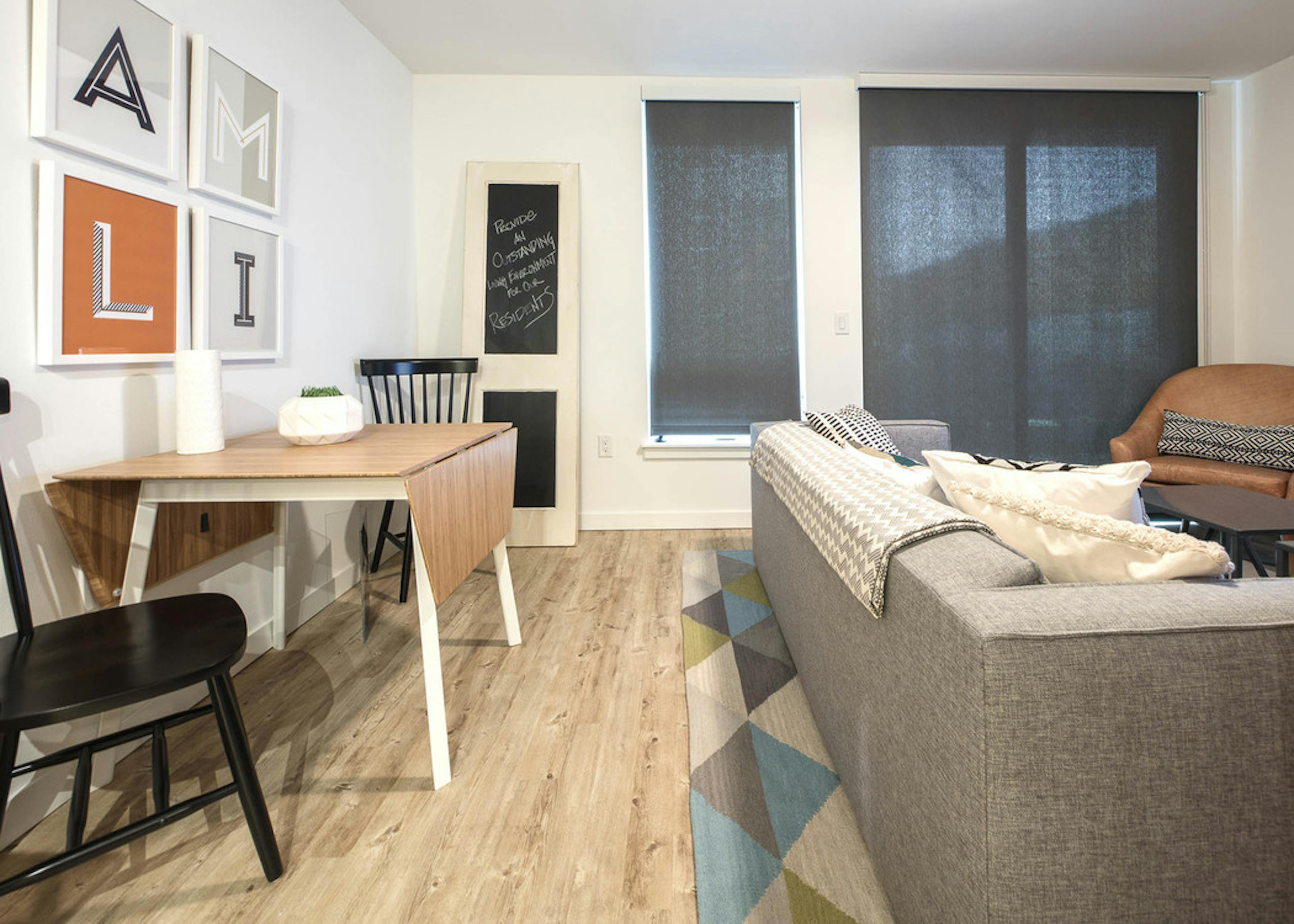 Interior AMLI Wallingford apartment living room with kitchen table and two chairs with a grey couch and solar shades 