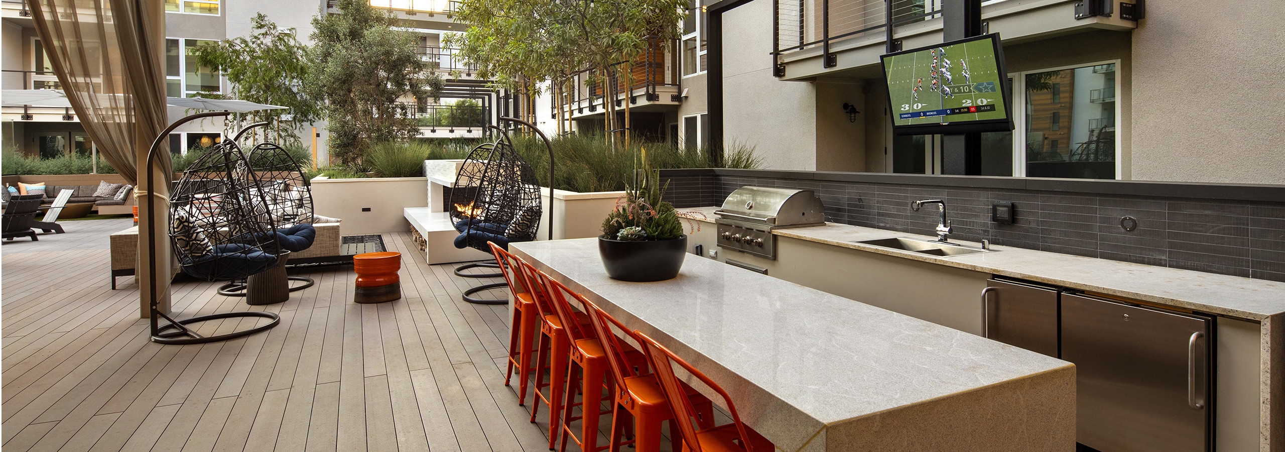 Entertaining grilling station with bar height quartz serving counter, chairs and TV at AMLI Marina Del Rey outdoor lanai