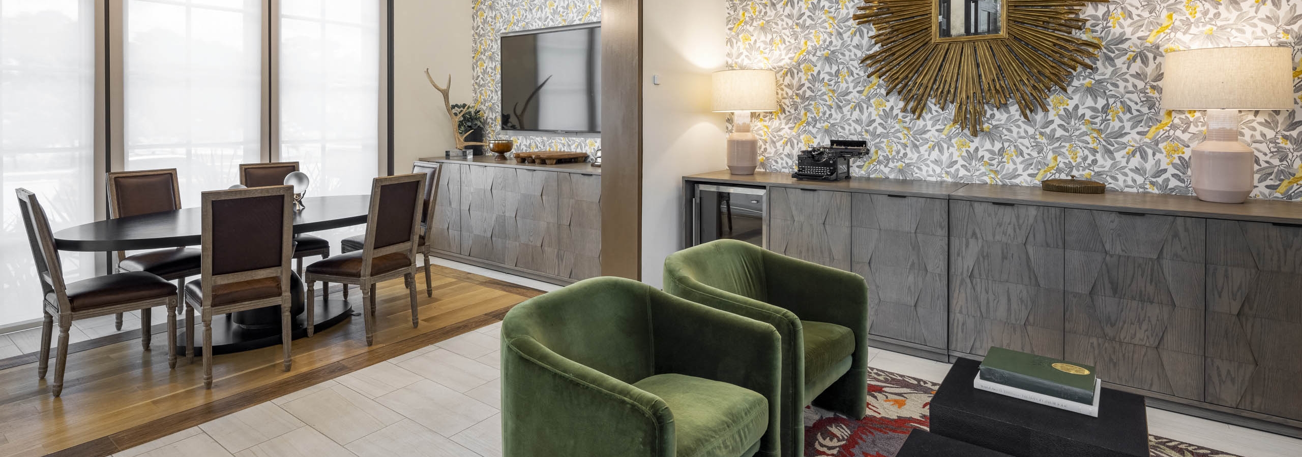 Business Center at AMLI Lakeline apartments including seating area with plush green chairs and an oval wooden conference table with wooden chairs