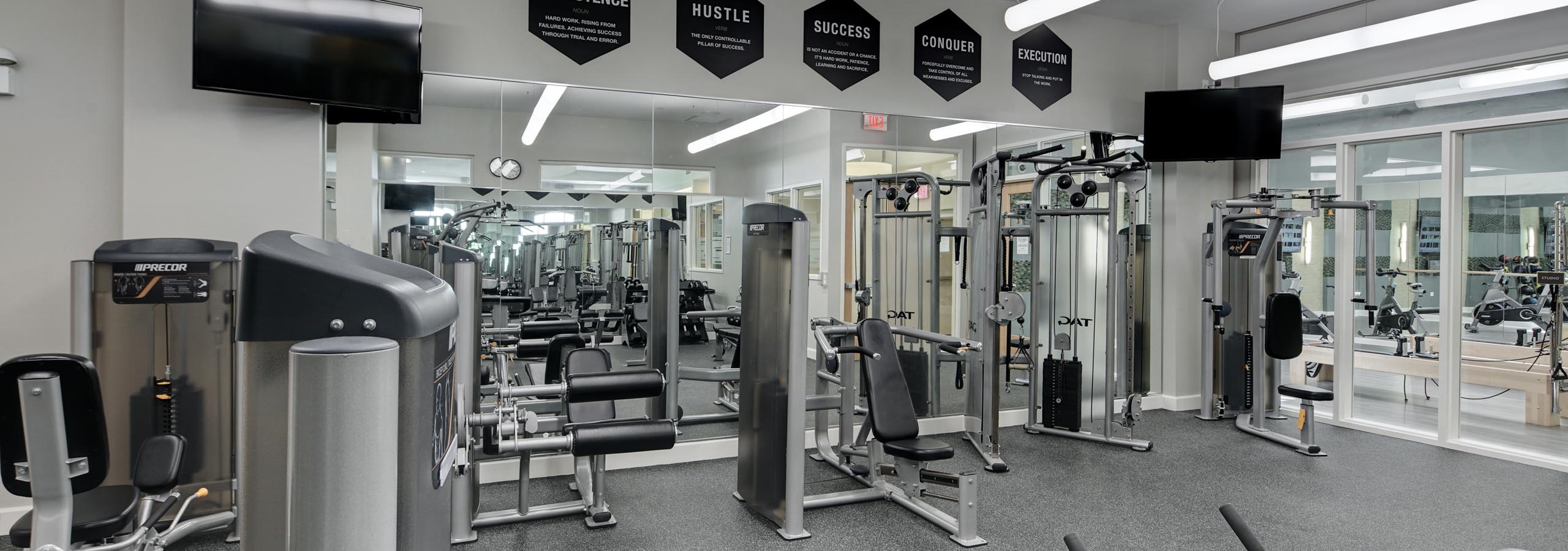 AMLI Evanston fitness center with weight machines lining mirrors spanning across an entire wall featuring two flat screen TVs