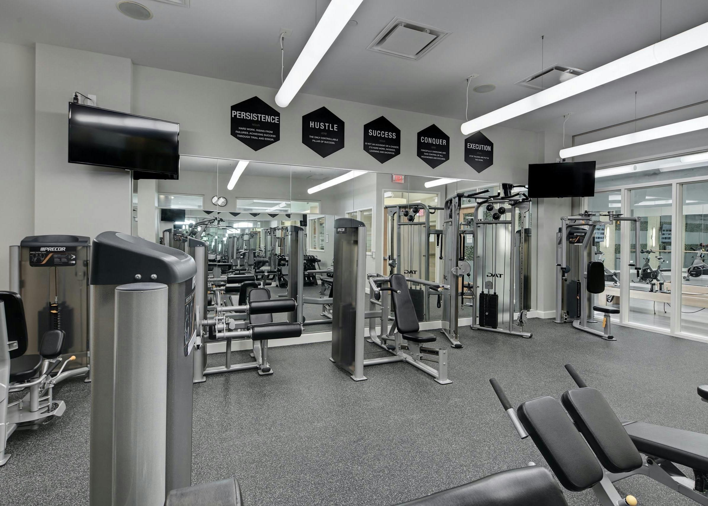 AMLI Evanston fitness center with weight machines lining mirrors spanning across an entire wall featuring two flat screen TVs