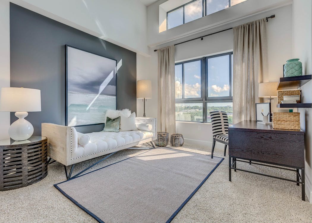 AMLI Joya den with natural light from window, a desk with chair and a white modern chaise lounge underneath a modern painting