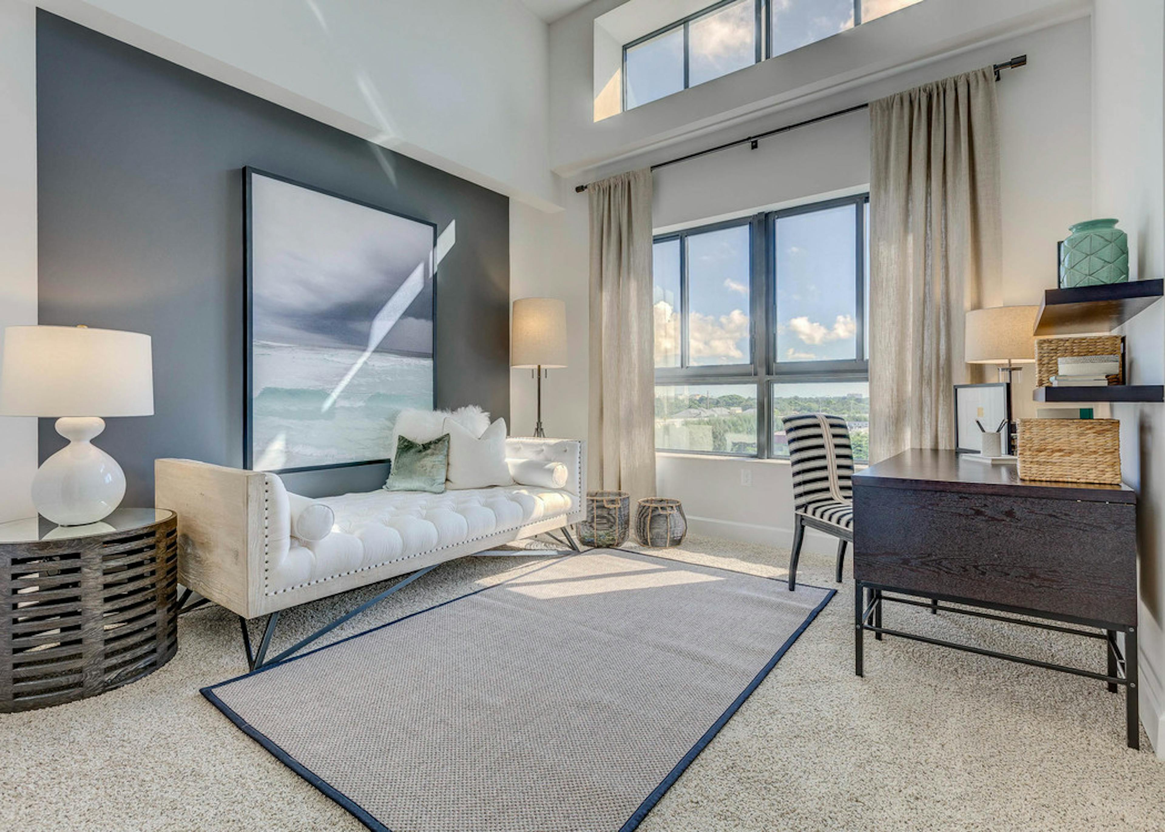 AMLI Joya den with natural light from window, a desk with chair and a white modern chaise lounge underneath a modern painting