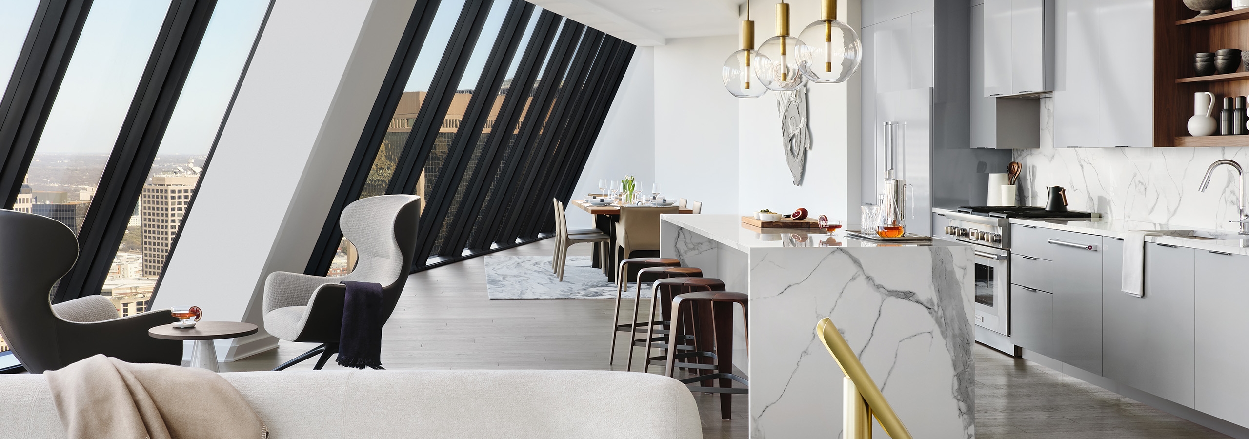 Kitchen with white stone island and gray cabinets and floor to ceiling sloped windows at AMLI Fountain Place apartments