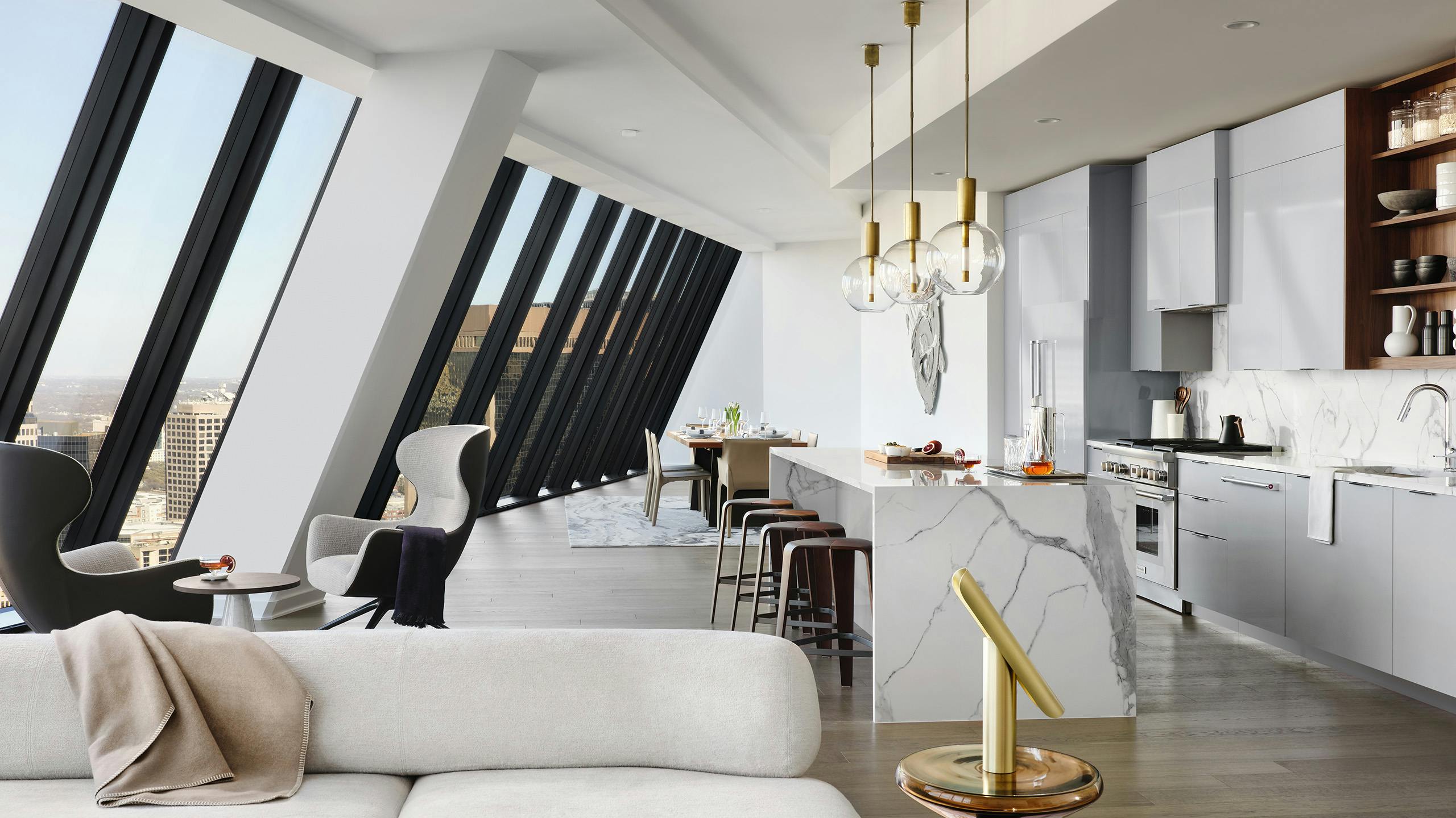 Kitchen with white stone island and gray cabinets and floor to ceiling sloped windows at AMLI Fountain Place apartments