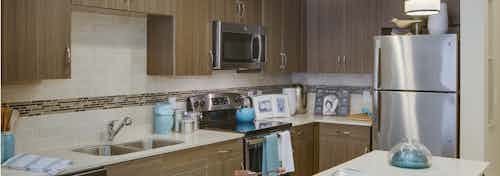 AMLI Ponce Park apartment kitchen showcasing stainless steel appliances nested in dark cabinets with white tile backsplash