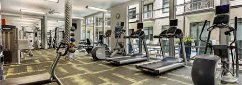 AMLI 5350 fitness center with treadmills facing tall windows and a variety of other exercise machines in the background