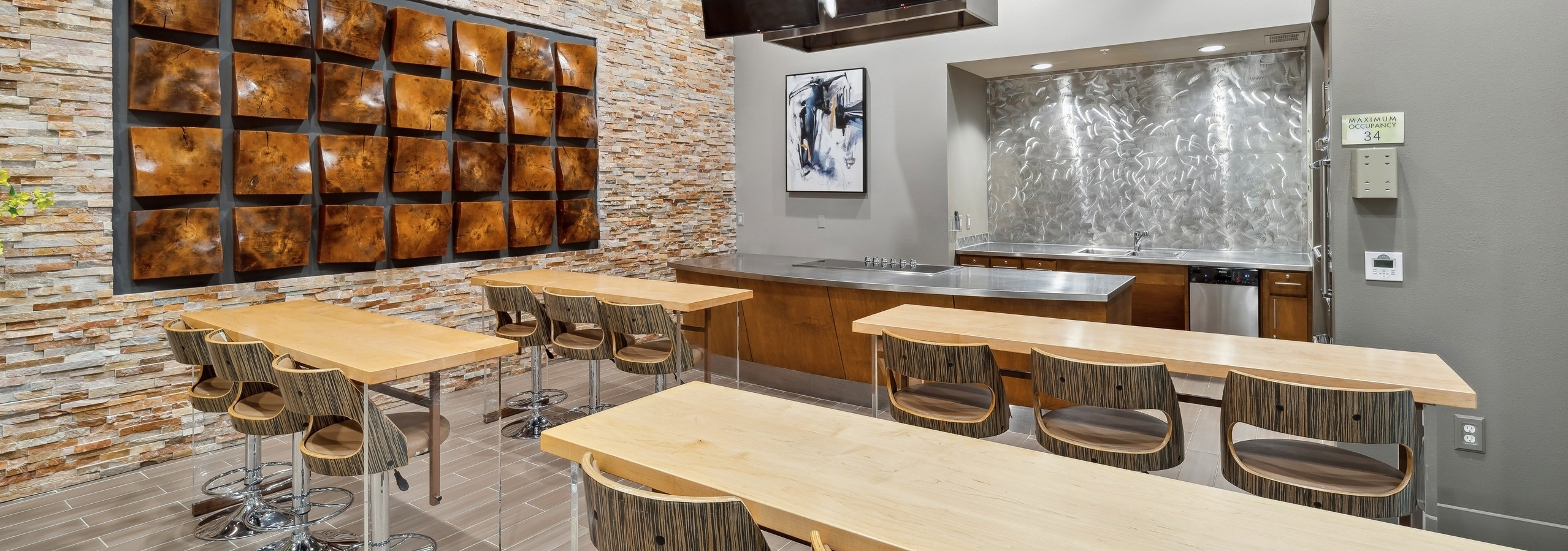 A demo kitchen at AMLI RidgeGate with a stainless steel countertop with stove and oven and high top tables with chairs