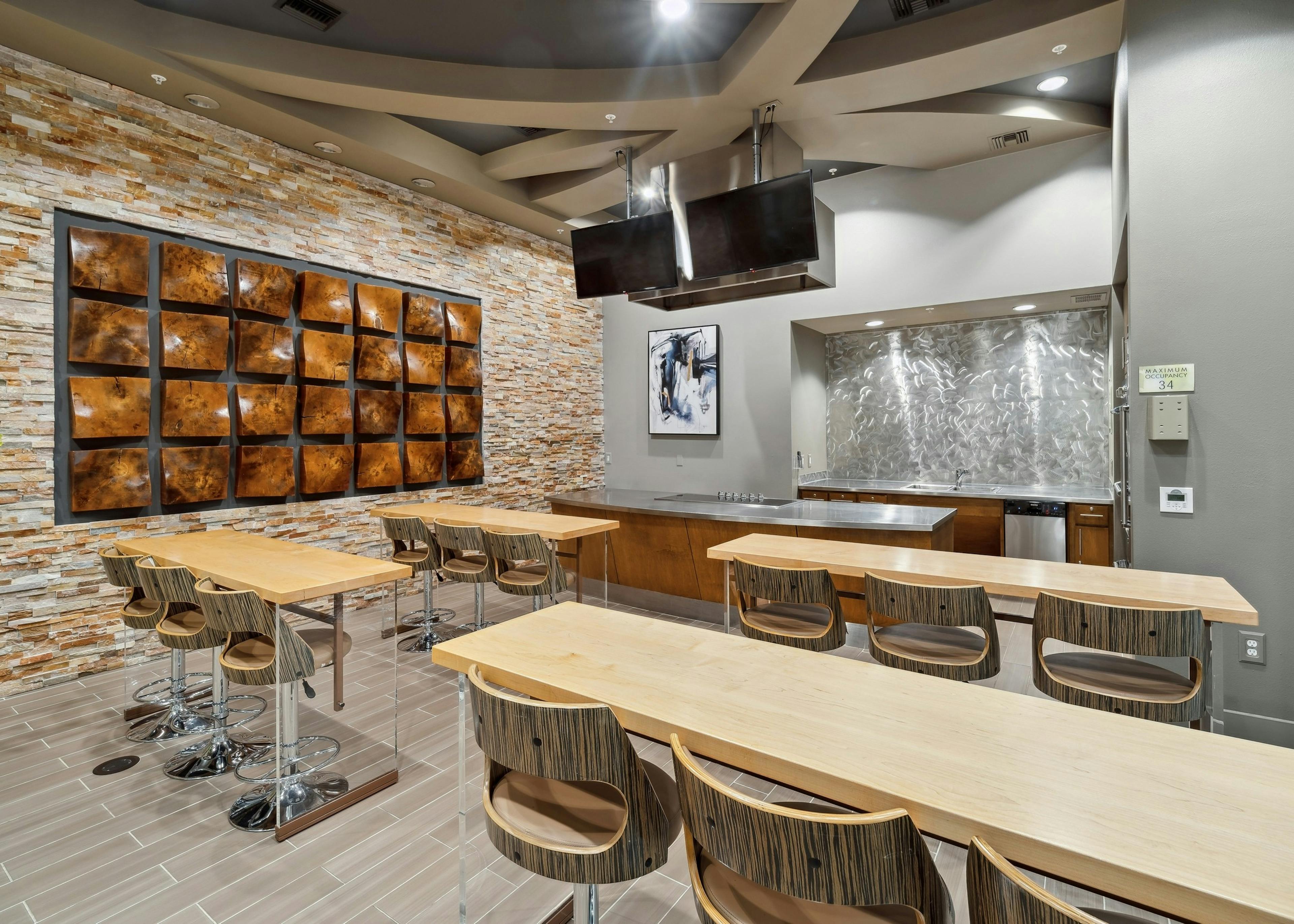 A demo kitchen at AMLI RidgeGate with a stainless steel countertop with stove and oven and high top tables with chairs