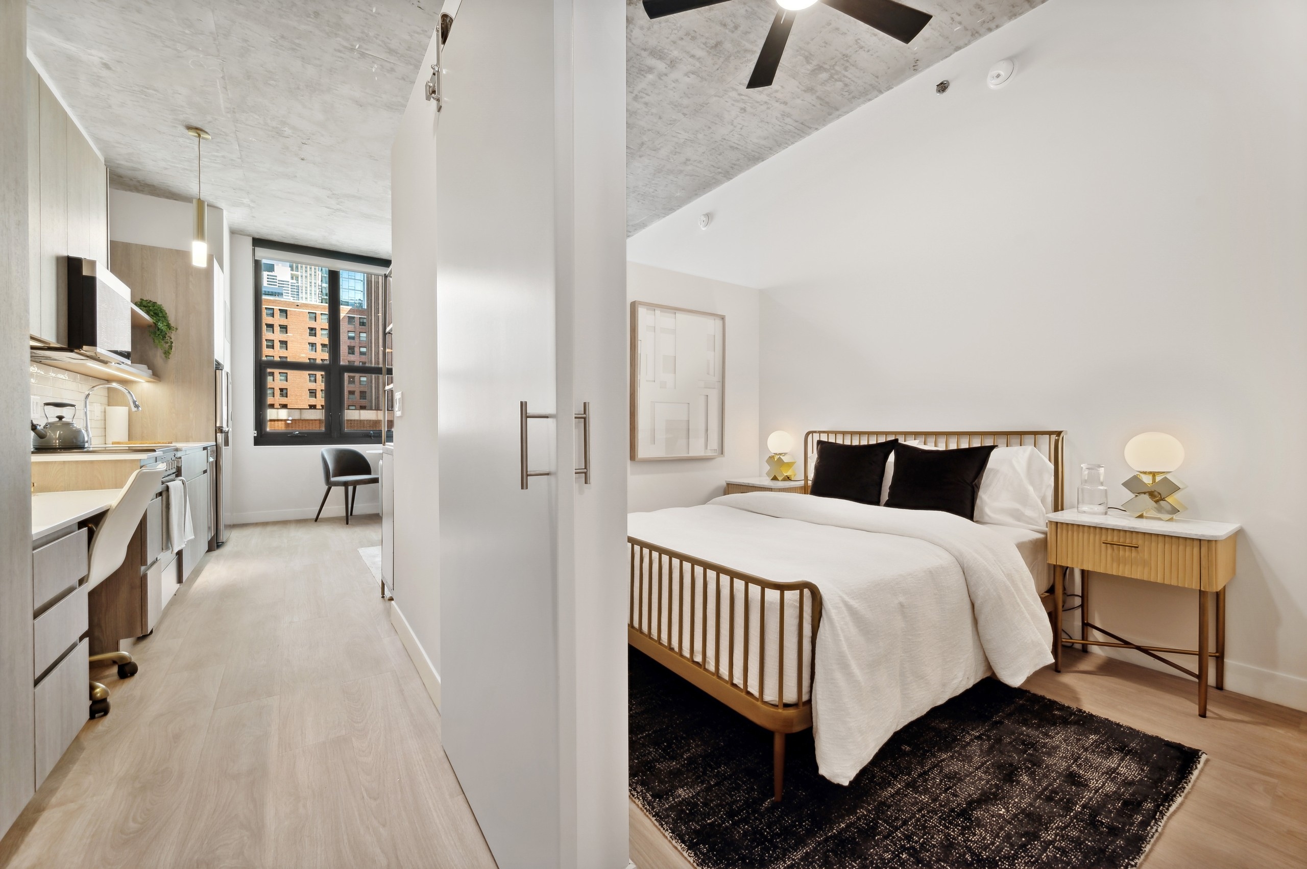 AMLI 808 bedroom with hallway and view to the city and bed with white bedding and wooden side table and distressed ceiling