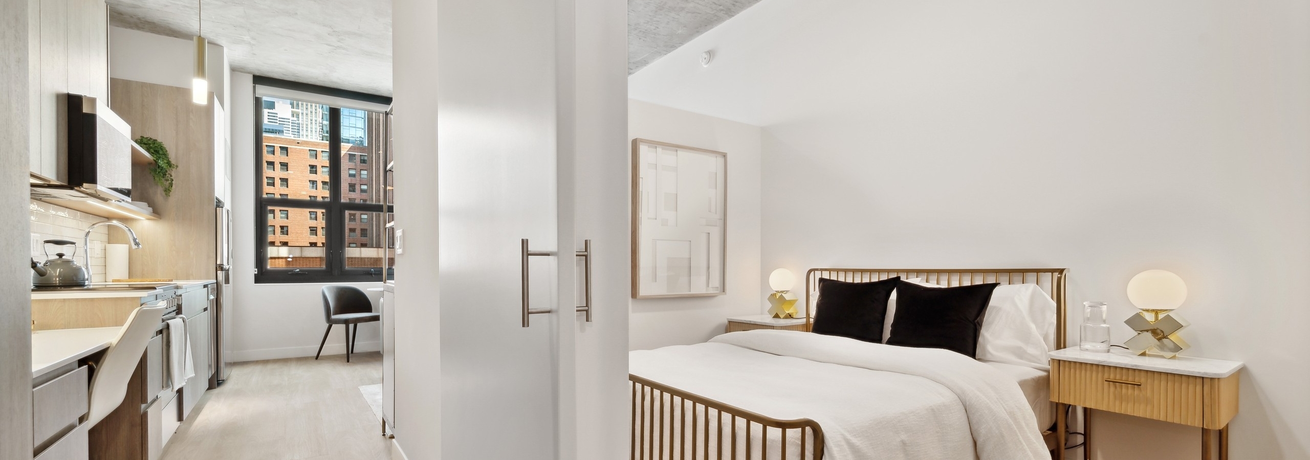 AMLI 808 bedroom with hallway and view to the city and bed with white bedding and wooden side table and distressed ceiling