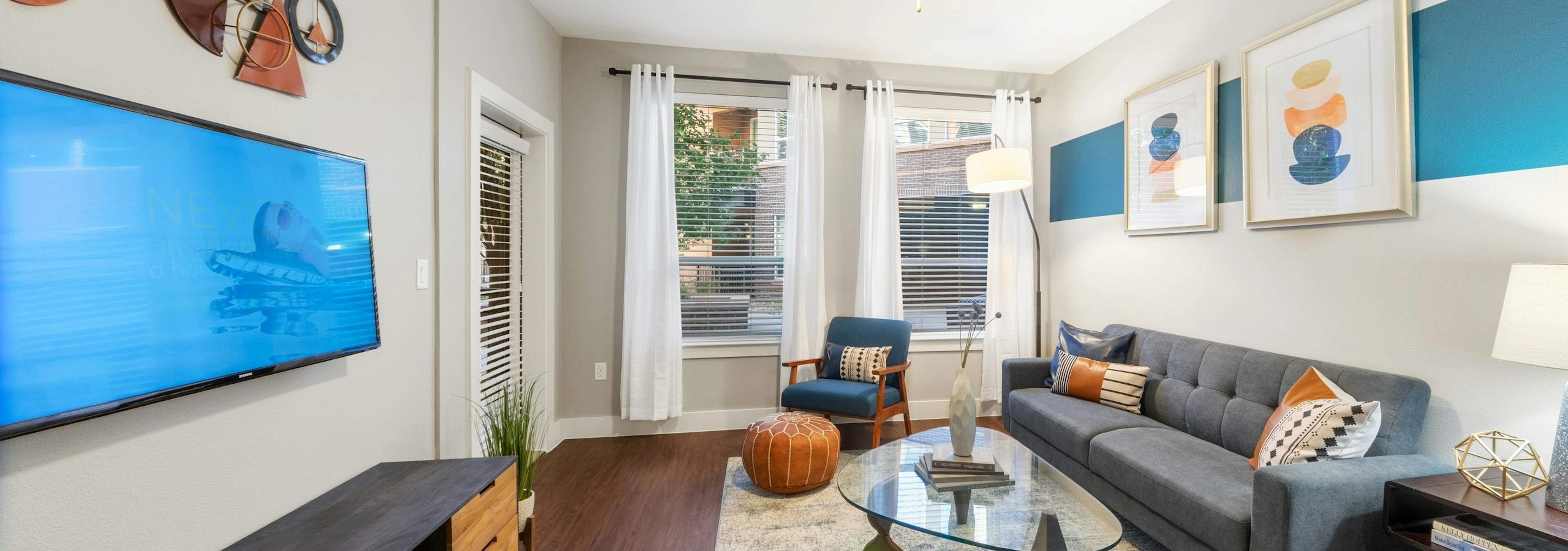 AMLI Riverfront Park living room with dark flooring and spacious bright windows featuring colorful furniture and decor pieces