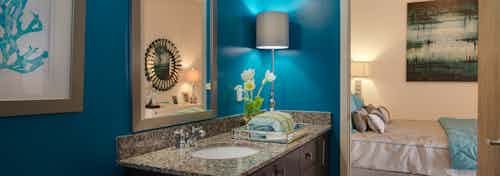 AMLI Old 4th Ward apartment bathroom with granite countertops and dark cabinetry with blue walls and a peek into the bedroom