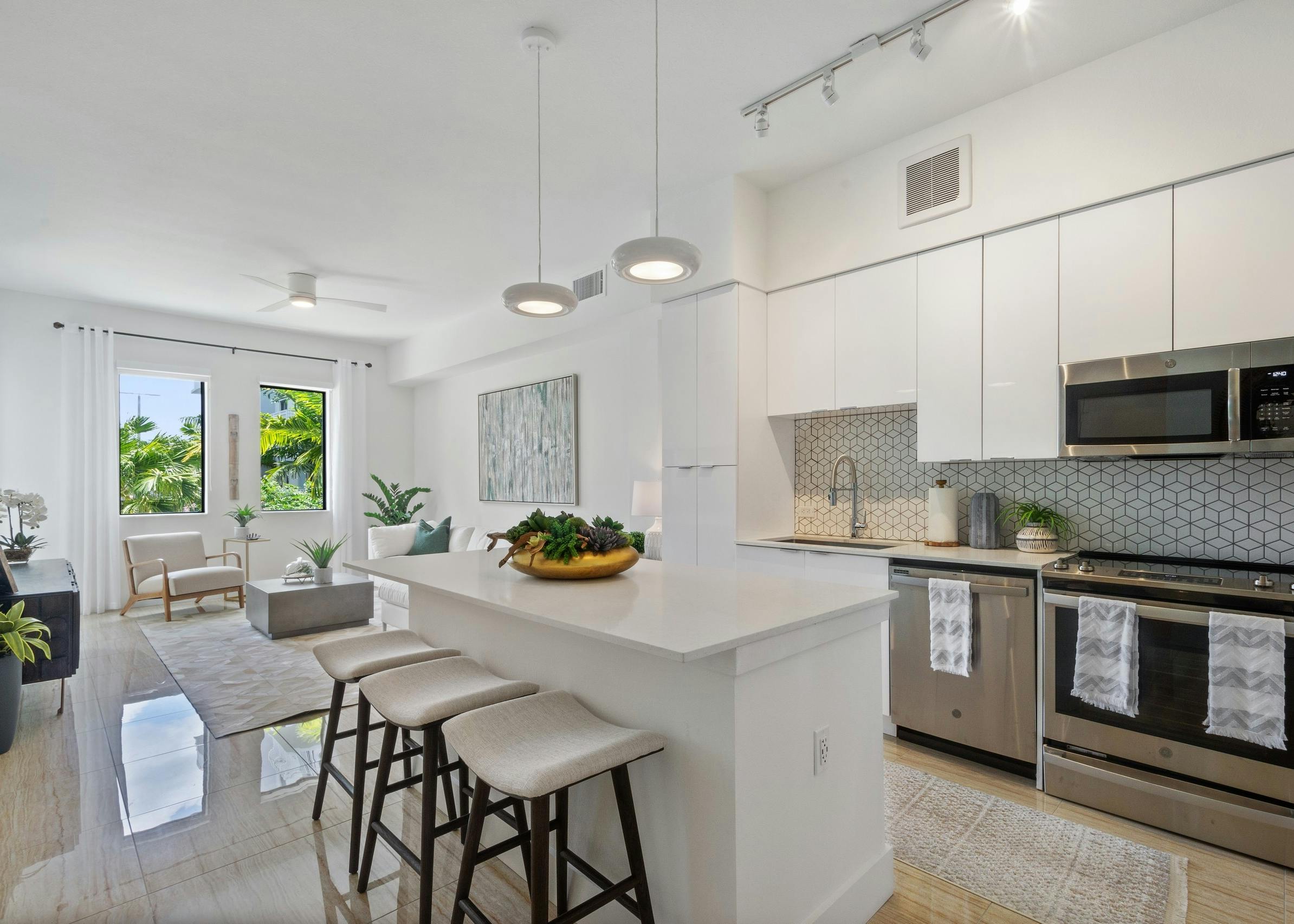 Kitchen at AMLI Park West apartments with white cabinets and island with stools and a peek into living area with side window