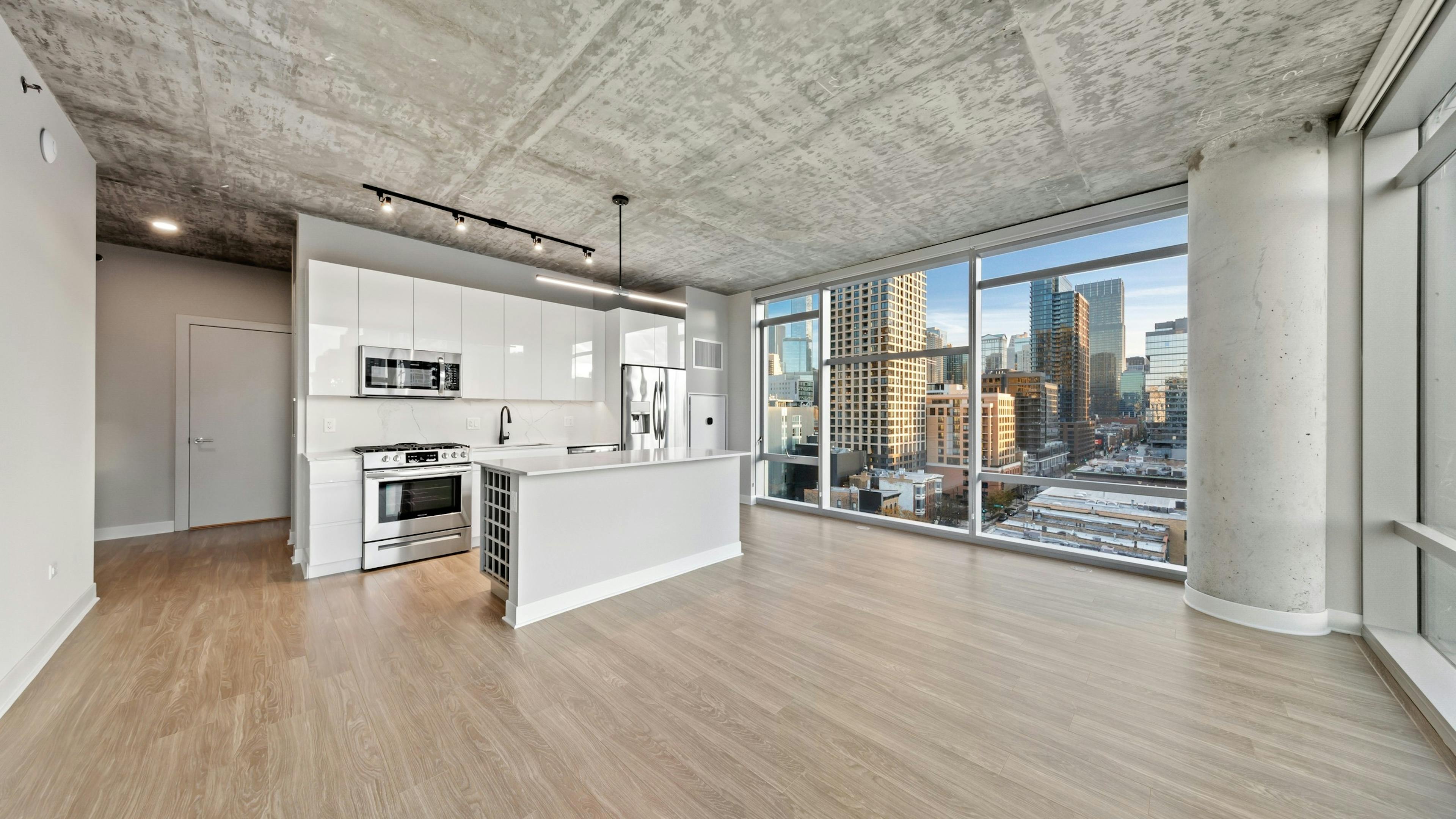 AMLI 808 apartment kitchen featuring all white sleek cabinetry and backsplash with floor to ceiling windows showing city view