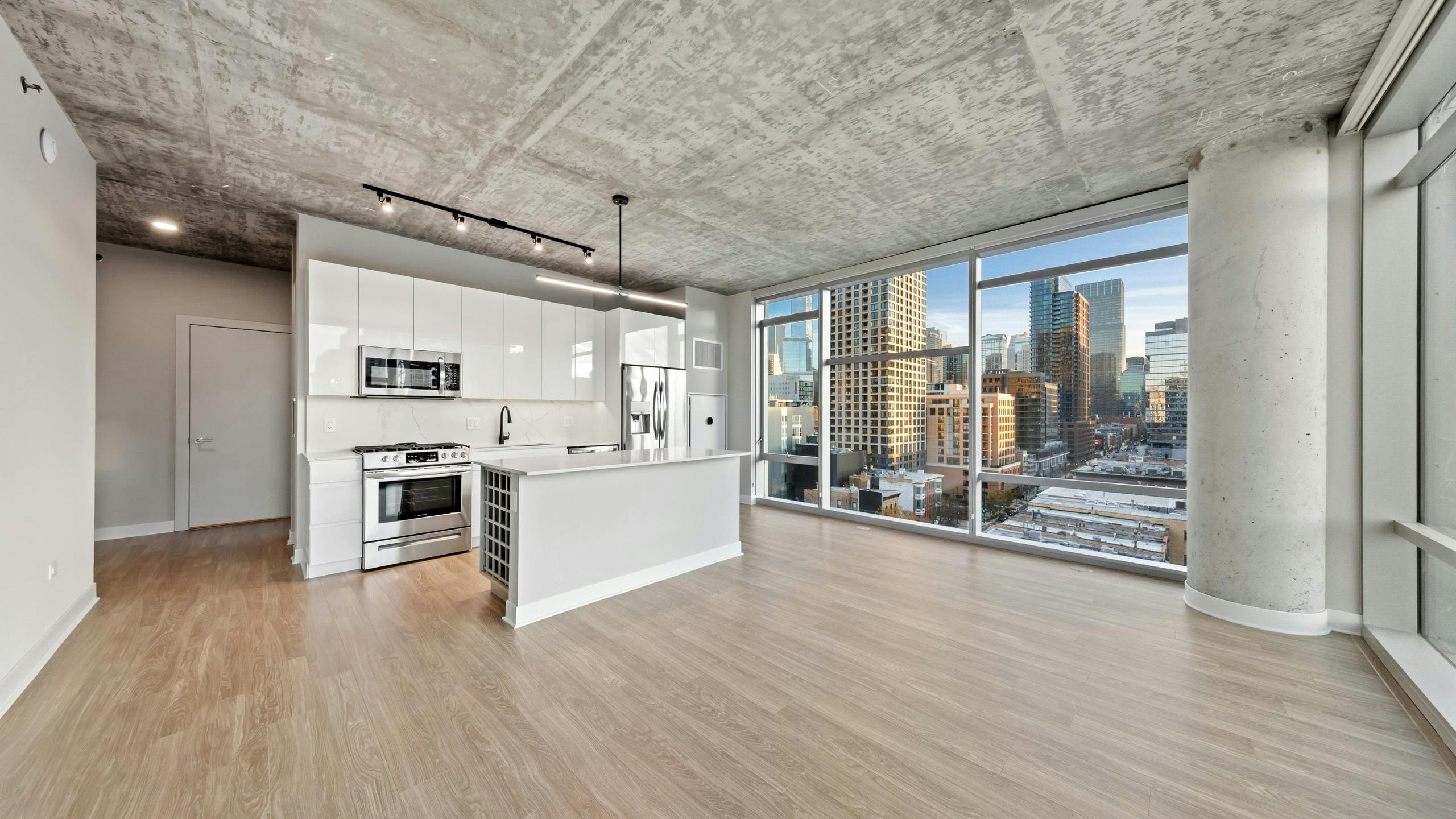 AMLI 808 apartment kitchen featuring all white sleek cabinetry and backsplash with floor to ceiling windows showing city view