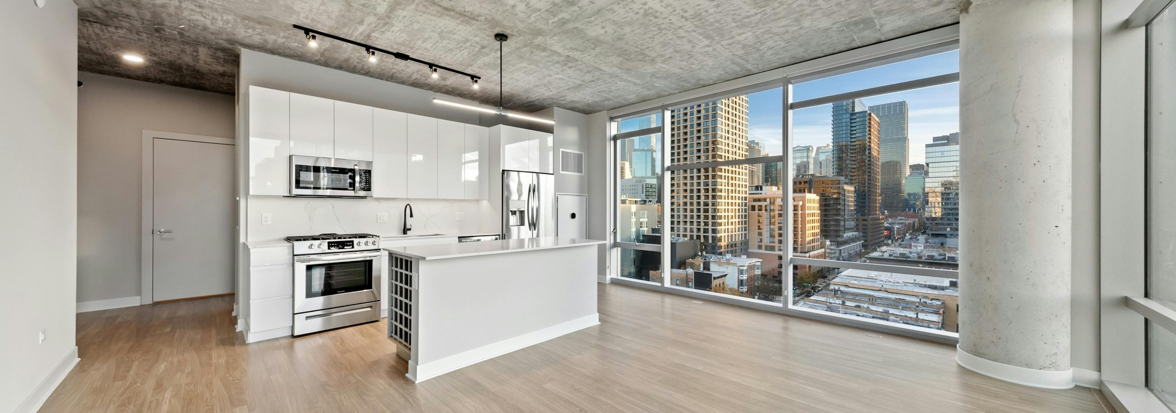 AMLI 808 apartment kitchen featuring all white sleek cabinetry and backsplash with floor to ceiling windows showing city view