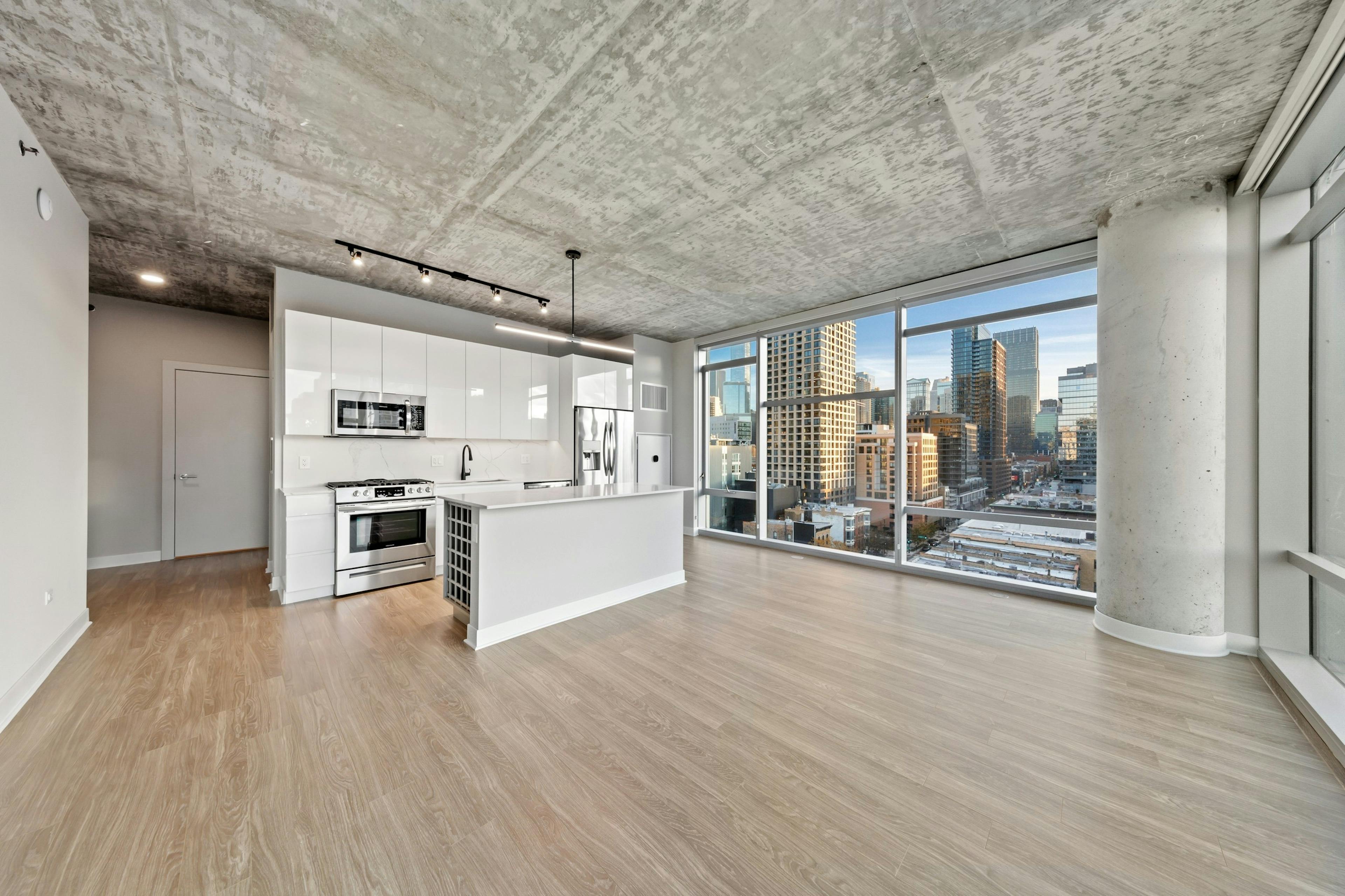 AMLI 808 apartment kitchen featuring all white sleek cabinetry and backsplash with floor to ceiling windows showing city view