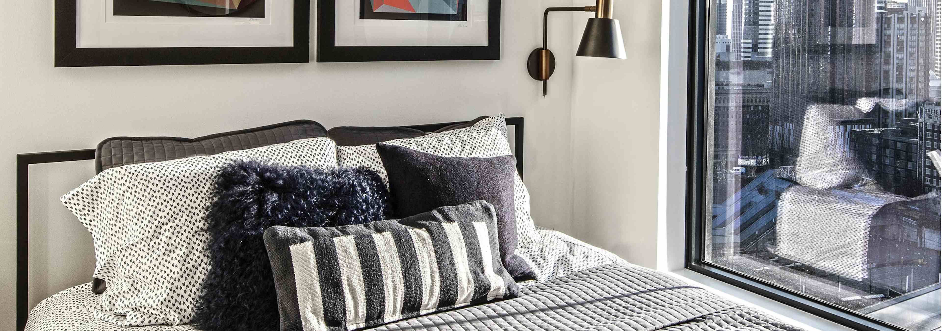 Interior view of a one bedroom apartment of AMLI Arc with white walls space for a queen bed and end tables and large window