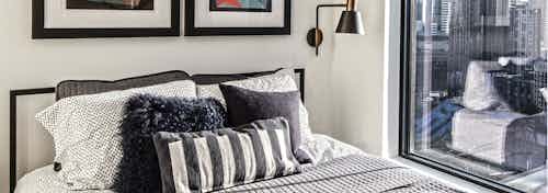 Interior view of a one bedroom apartment of AMLI Arc with white walls space for a queen bed and end tables and large window