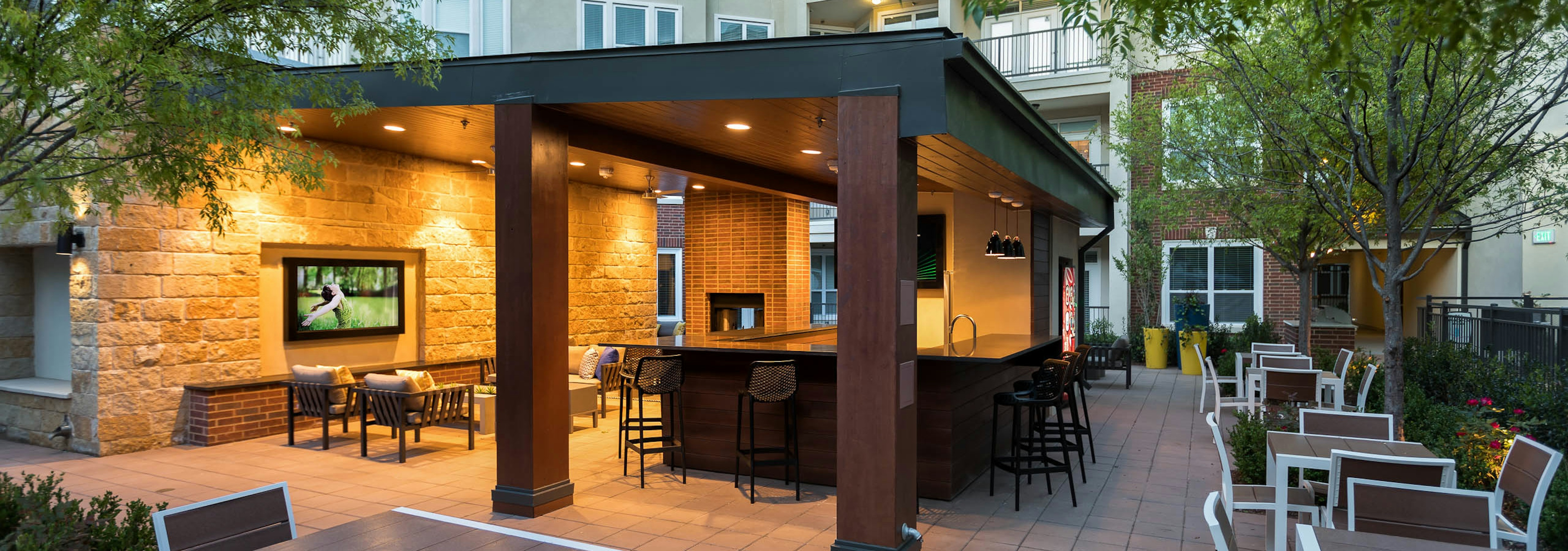 Nighttime view of cabana at AMLI Frisco Crossing apartments with serving bar and surrounding tables and chairs