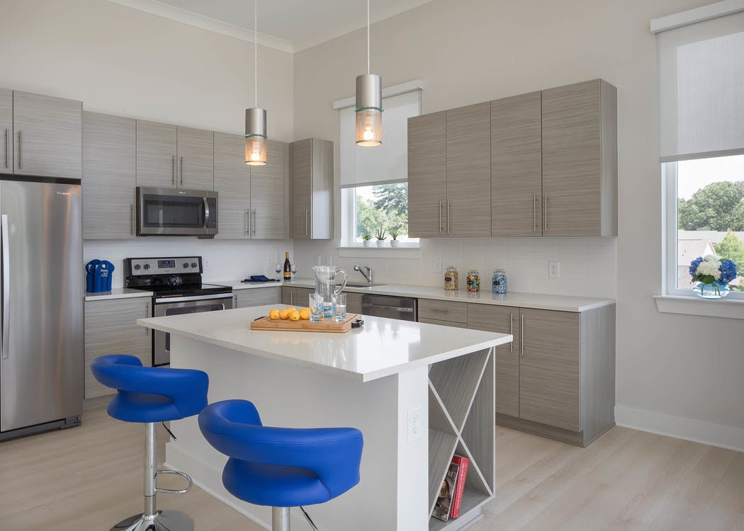 Interior of AMLI Buckhead kitchen with grey cabinets and sleek white countertops with stainless steel appliances and island