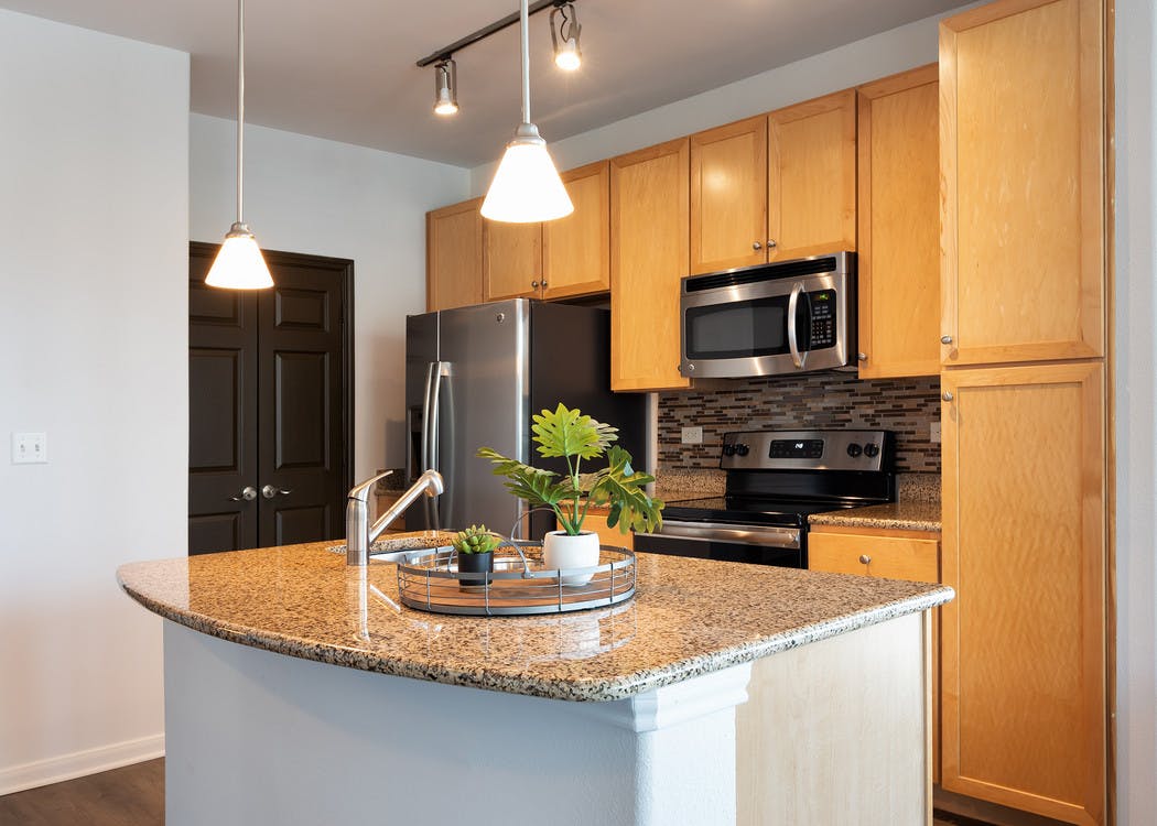 Interior view of AMLI 300 apartment kitchen with an island, custom wood cabinetry and stainless steel appliances