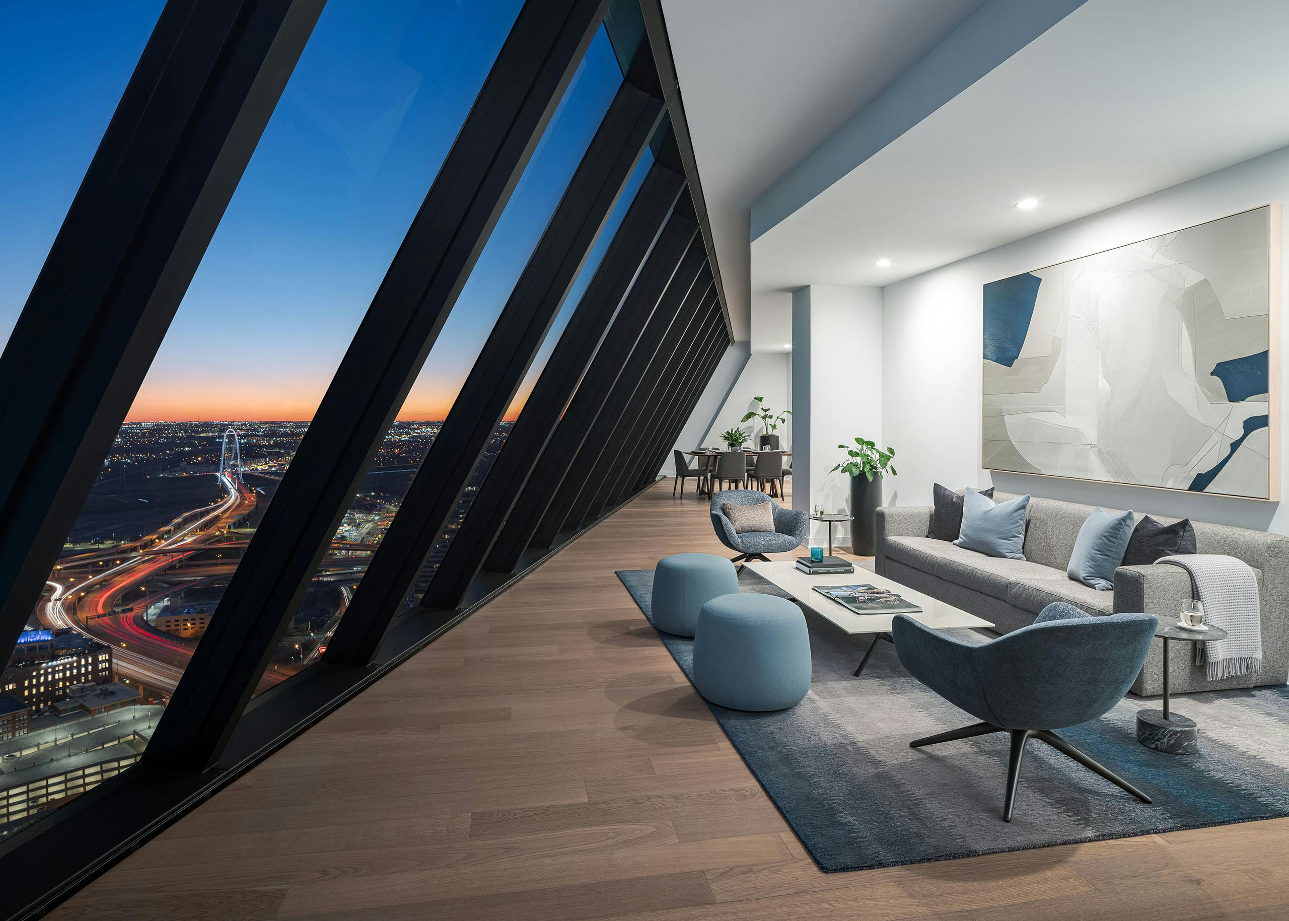 Penthouse living room at night with floor to ceiling windows sloped over couch and 2 chairs at AMLI Fountain Place apartments