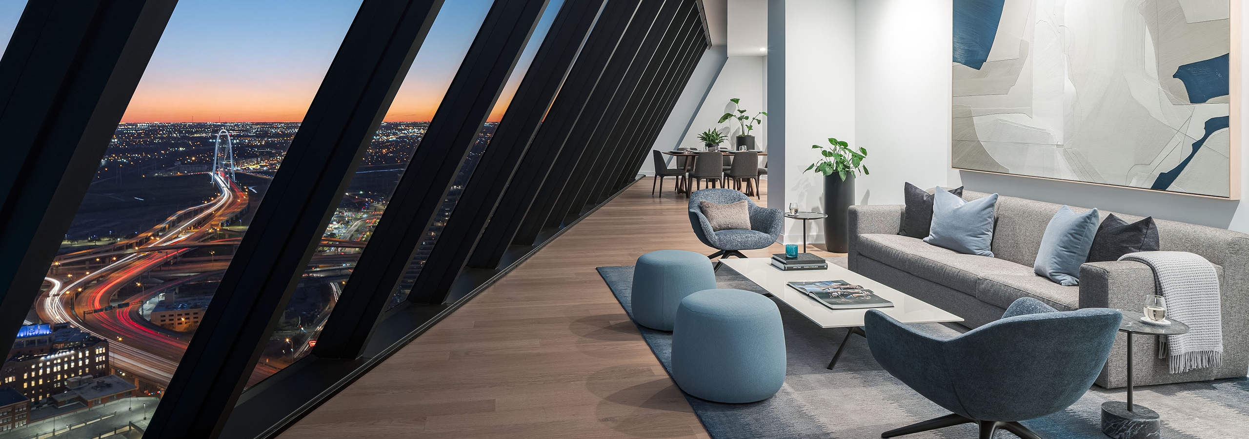 Penthouse living room at night with floor to ceiling  windows sloped over couch and 2 chairs at AMLI Fountain Place apartments