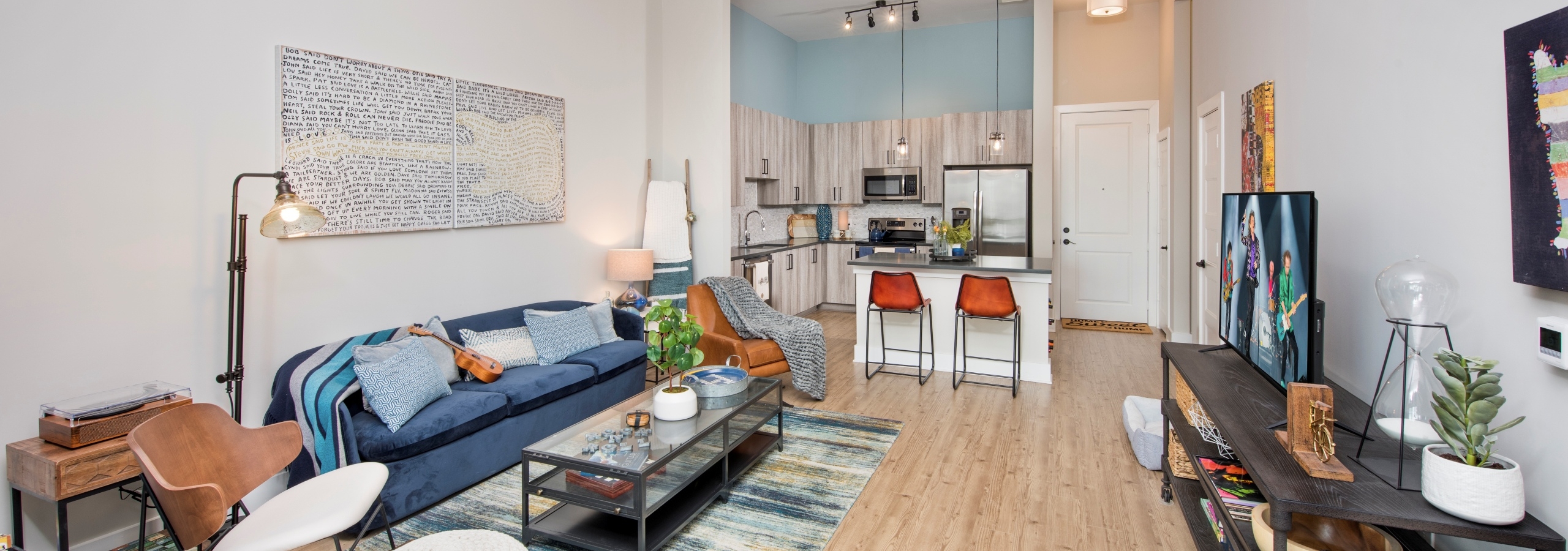 Interior of AMLI Decatur apartment living room with colorful furniture and light wood floors leading to island kitchen