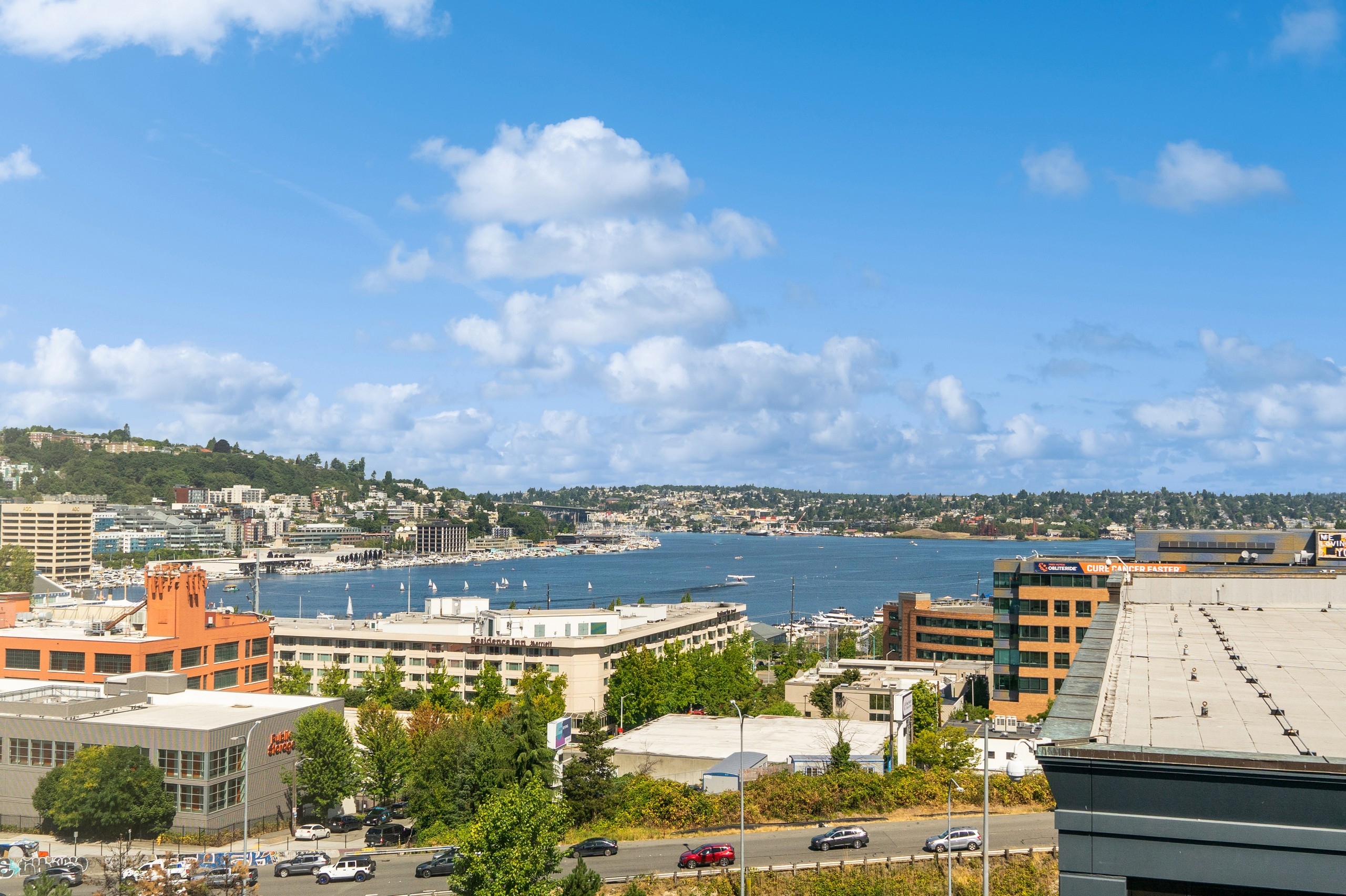 View from AMLI South Lake Union apartments with buildings surrounding lake under a blue sky with a few clouds