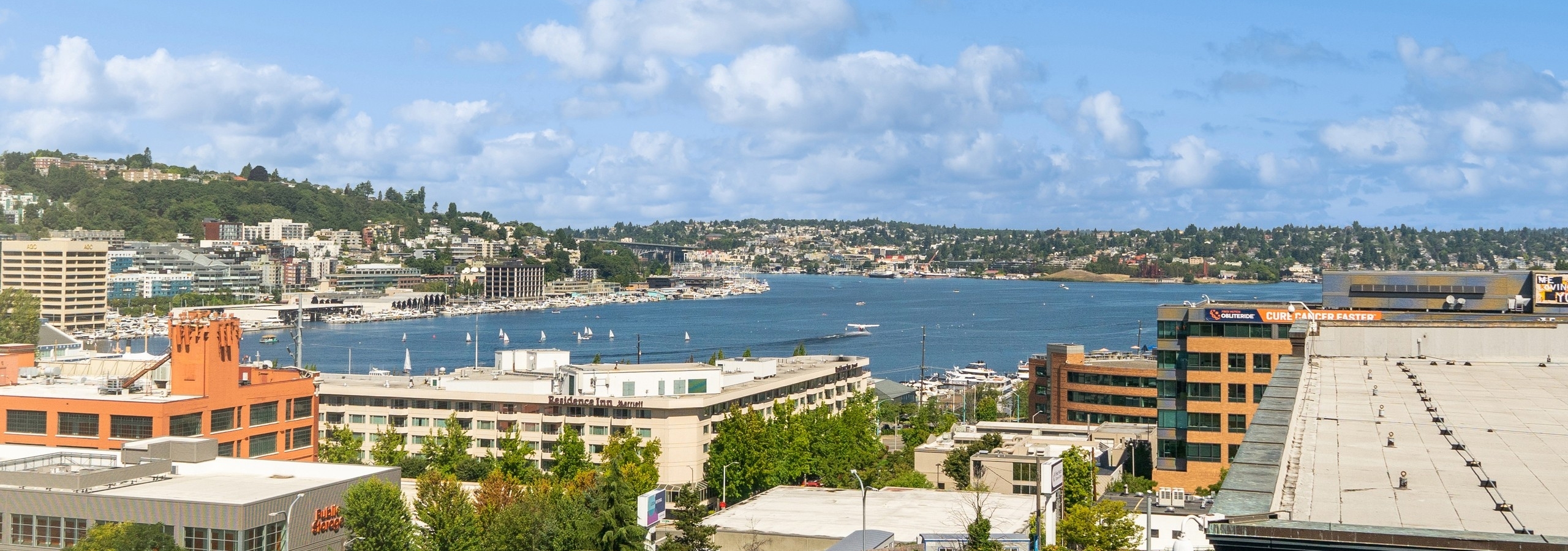 View from AMLI South Lake Union apartments with buildings surrounding lake under a blue sky with a few clouds