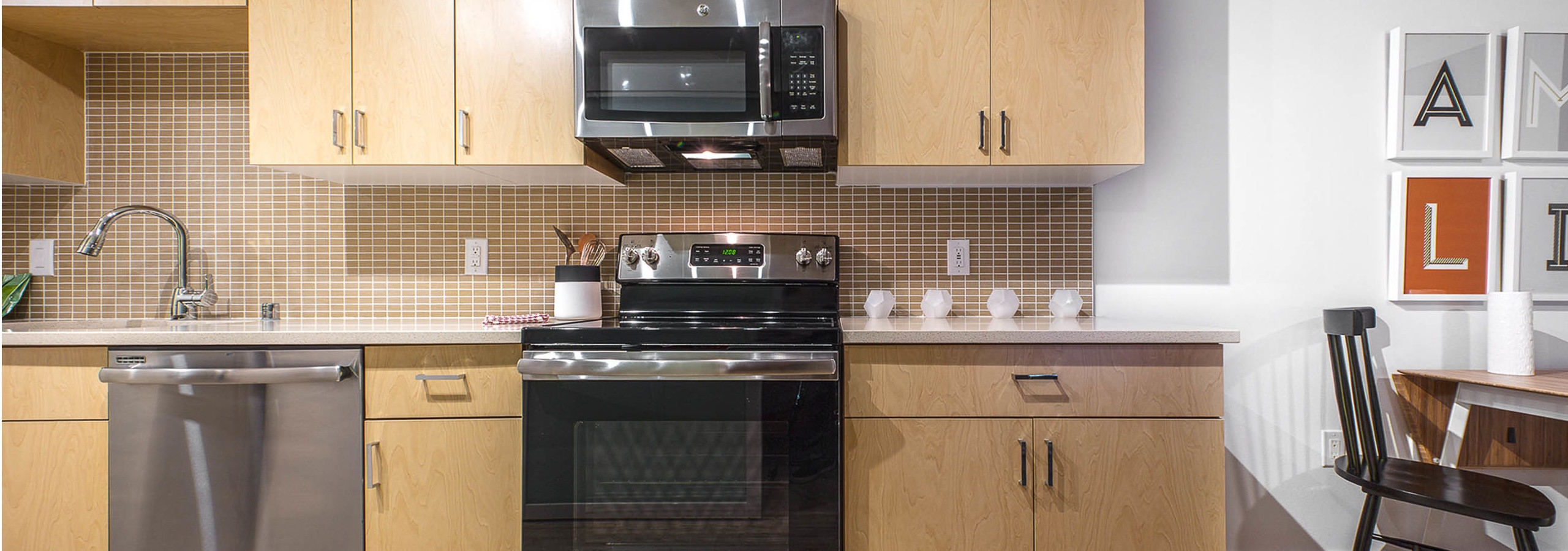 Interior view of an AMLI Wallingford apartment kitchen with light cabinets white quartz counter tops and stainless steel appliances