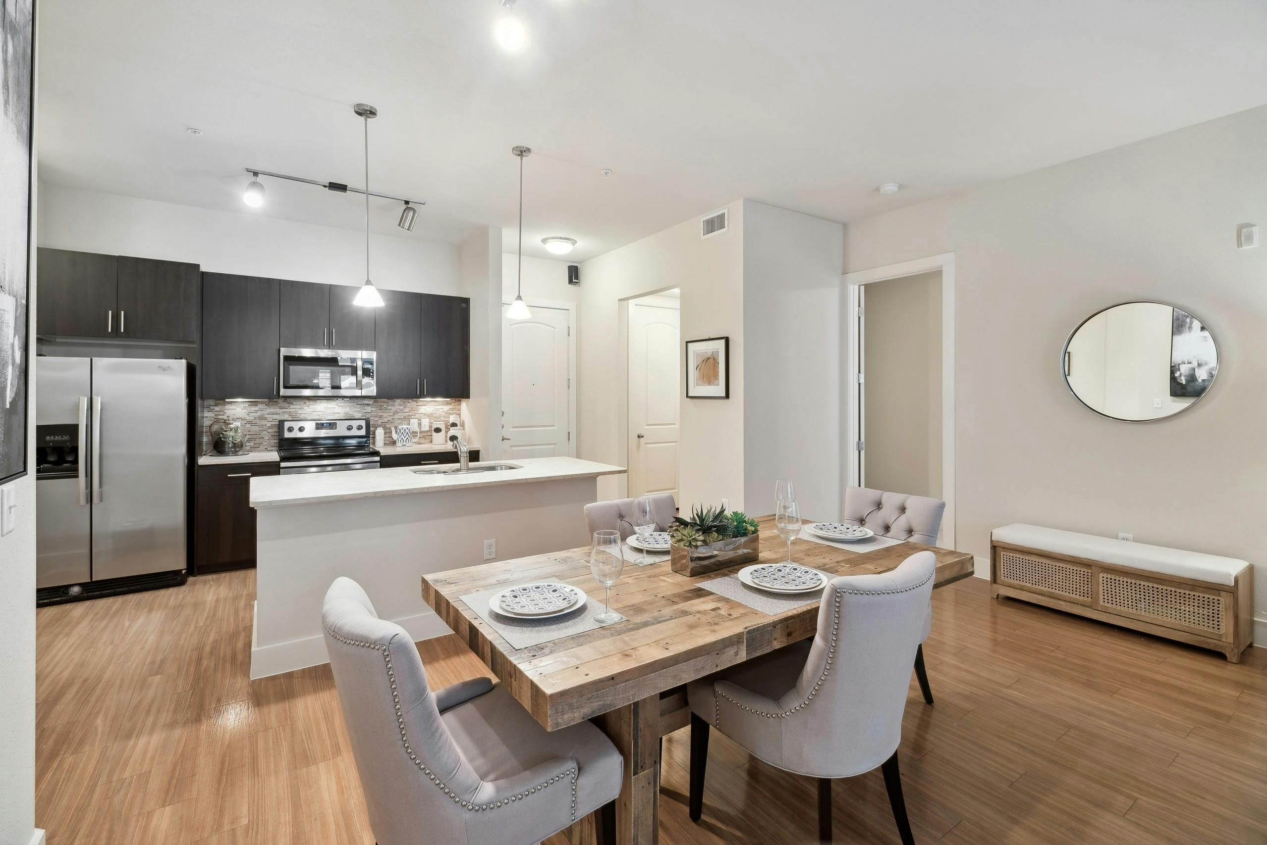 A kitchen and dining room at AMLI RidgeGate with plank flooring and an island countertop and a fridge and stove and microwave
