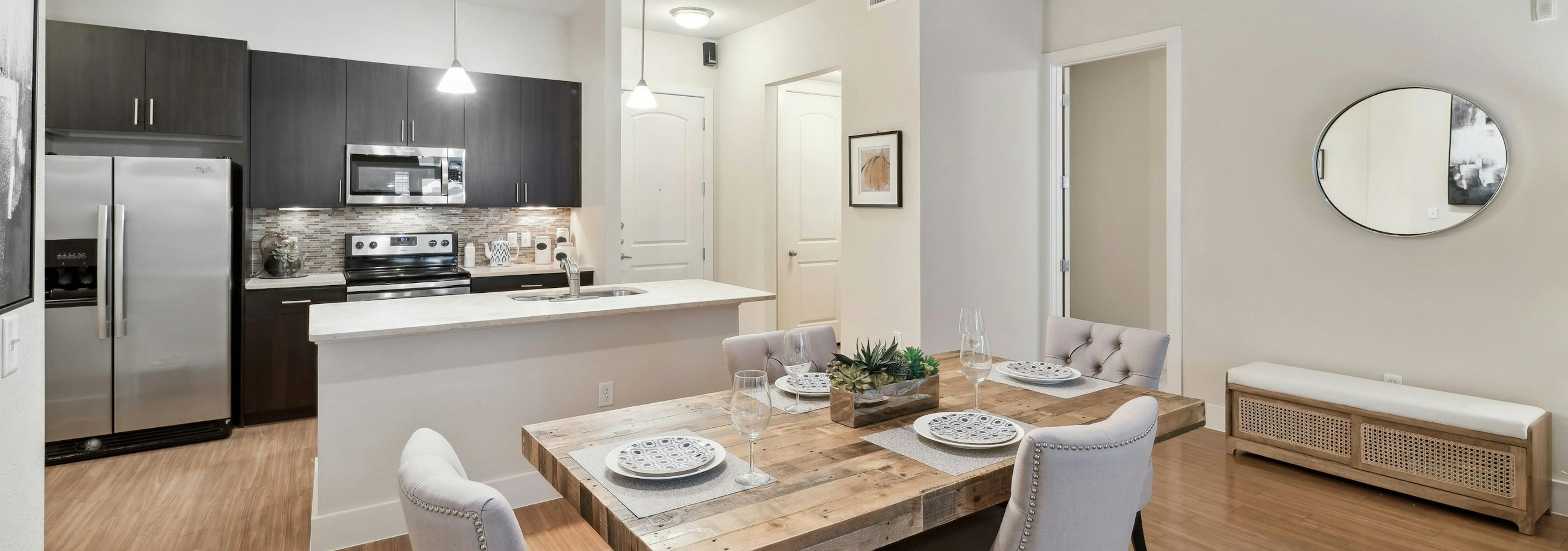 A kitchen and dining room at AMLI RidgeGate with plank flooring and an island countertop and a fridge and stove and microwave