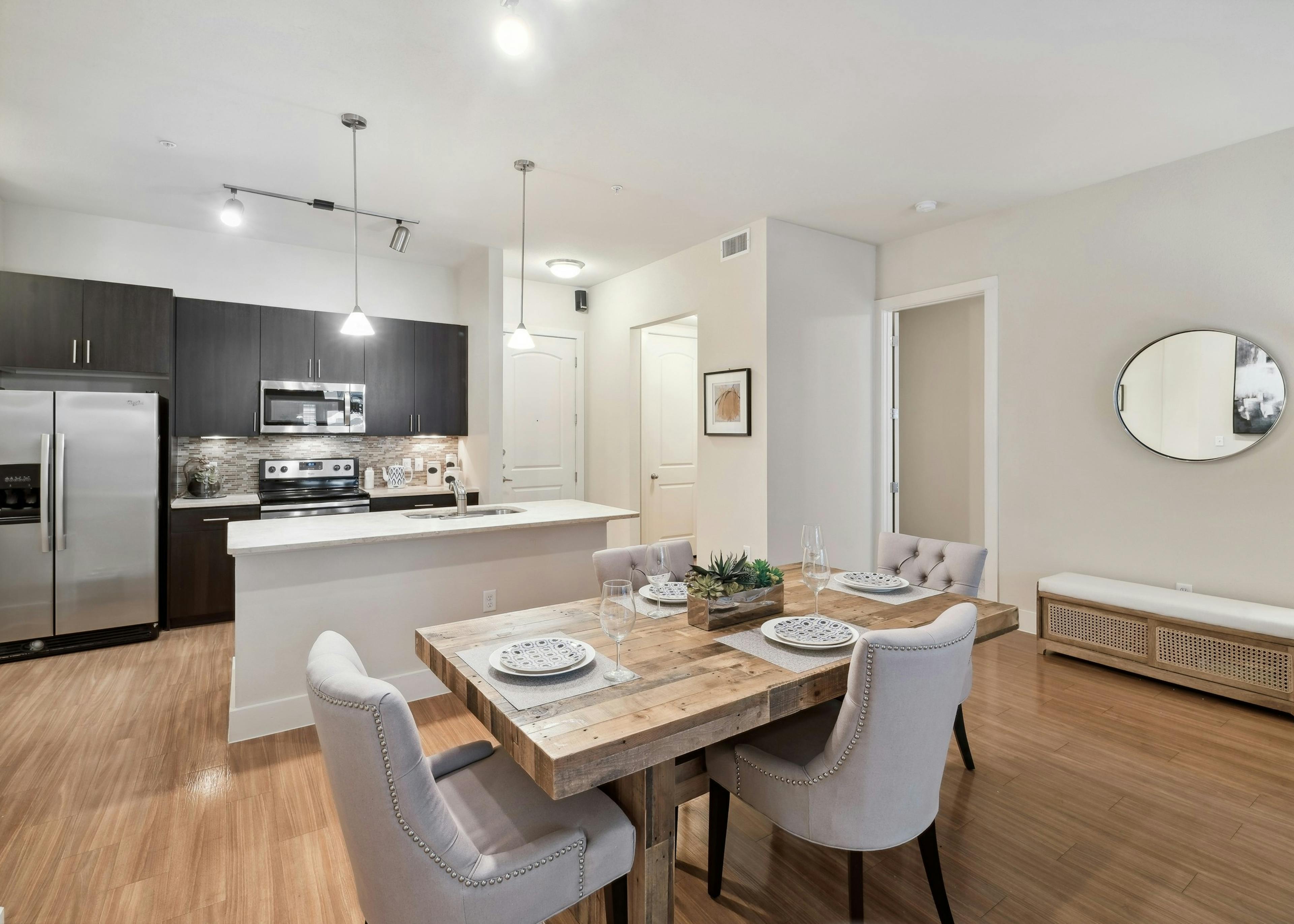 A kitchen and dining room at AMLI RidgeGate with plank flooring and an island countertop and a fridge and stove and microwave