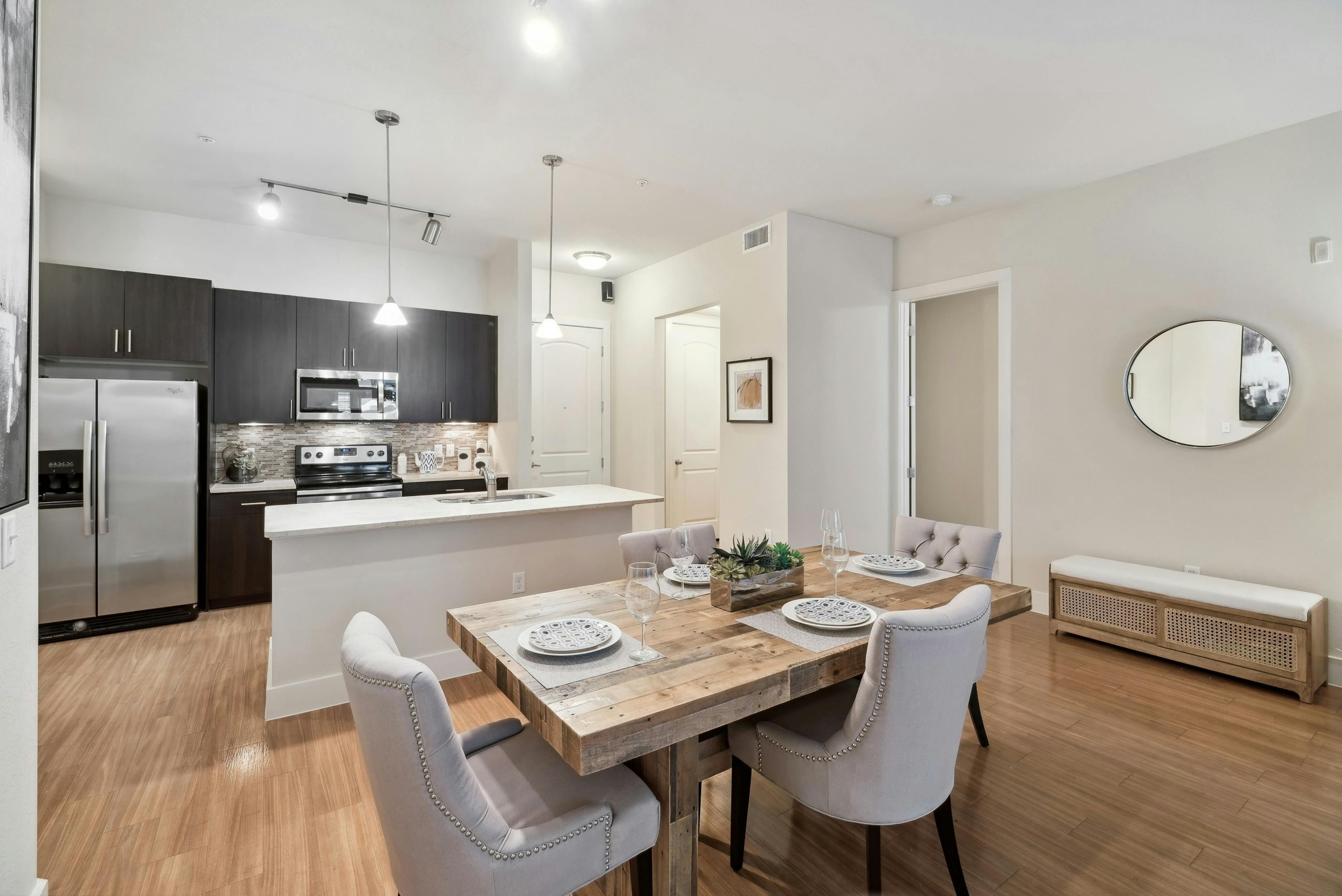 A kitchen and dining room at AMLI RidgeGate with plank flooring and an island countertop and a fridge and stove and microwave