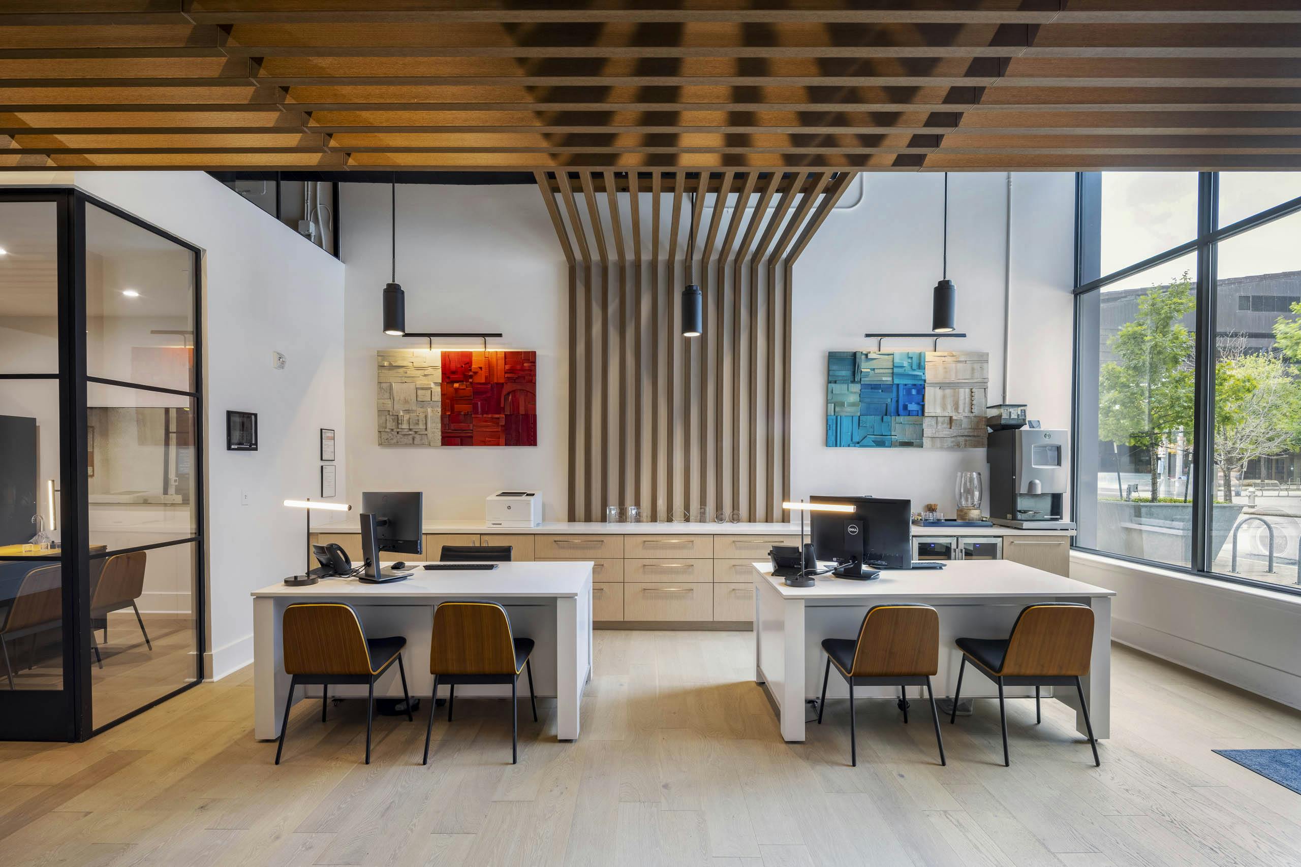 Leasing office at AMLI Downtown apartments with large street facing windows and two leasing desks with wooden chairs