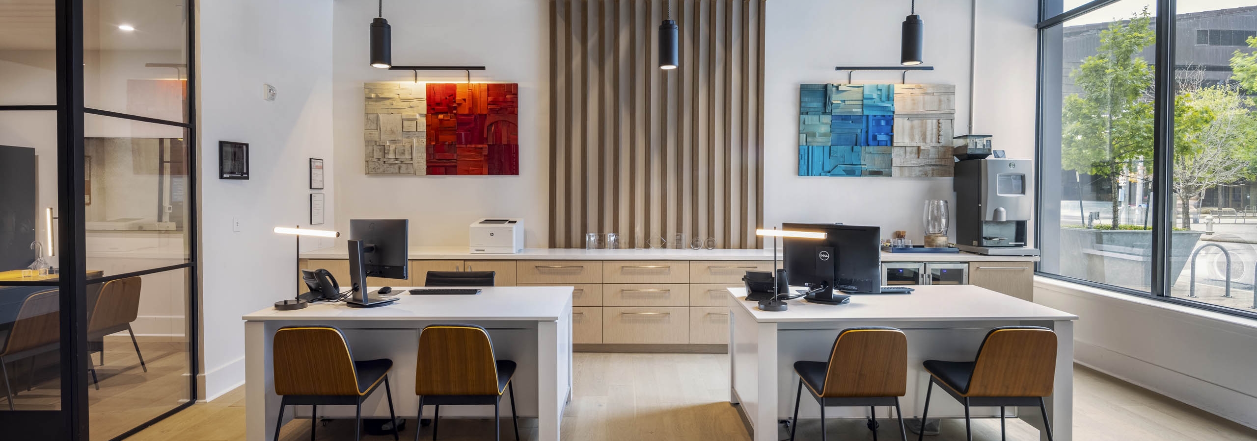 Leasing office at AMLI Downtown apartments with large street facing windows and two leasing desks with wooden chairs
