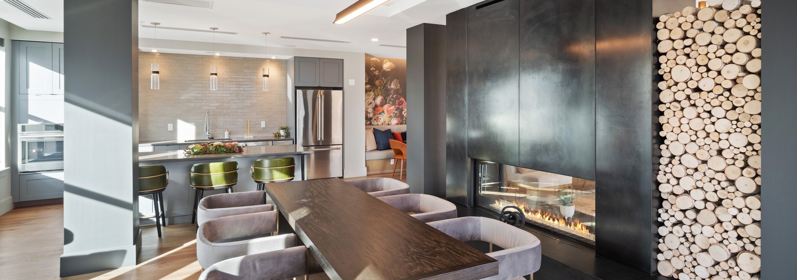 Close up of modern grey chairs at a wooden table in front of luxurious black fireplace in AMLI at Uptown resident lounge