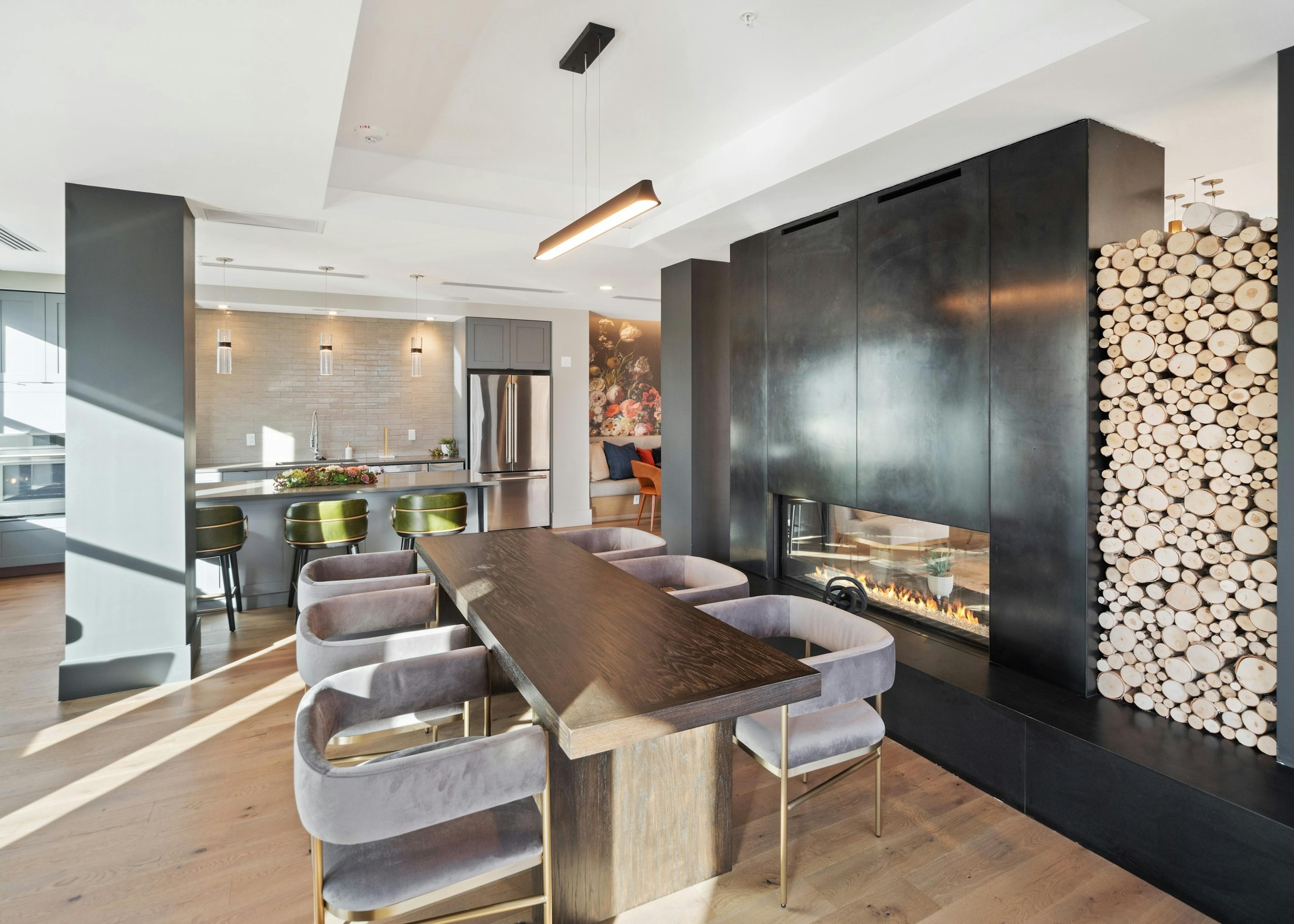 Close up of modern grey chairs at a wooden table in front of luxurious black fireplace in AMLI at Uptown resident lounge 