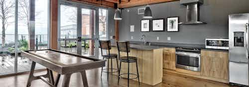Interior view of rooftop clubroom at the AMLI Mark24 apartment building with kitchen and shuffleboard table and wood rafters
