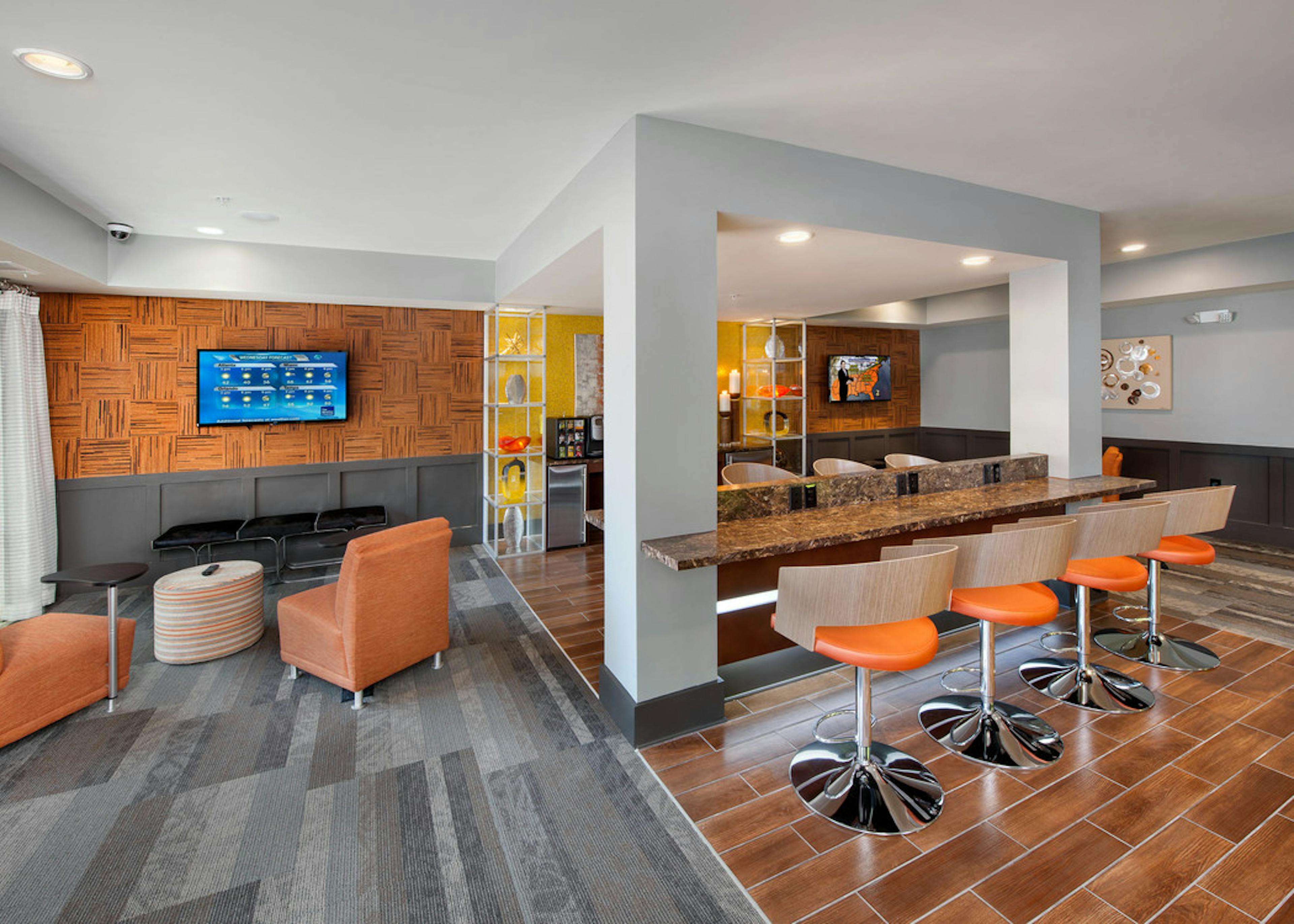 AMLI Piedmont Heights colorful clubroom showcasing counter space with barstools and seating area looking at large TV on wall