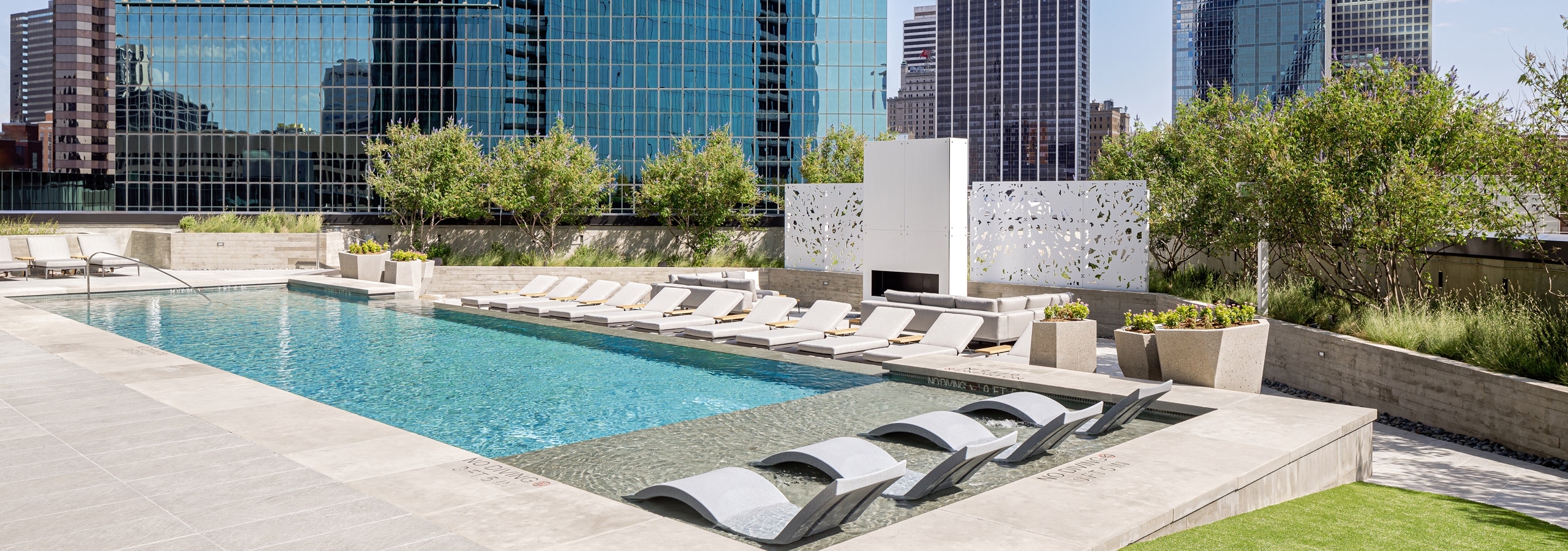 AMLI at Fountain Place landscaped rooftop swimming pool surrounded by lounge chairs on 3 sides and large office buildings