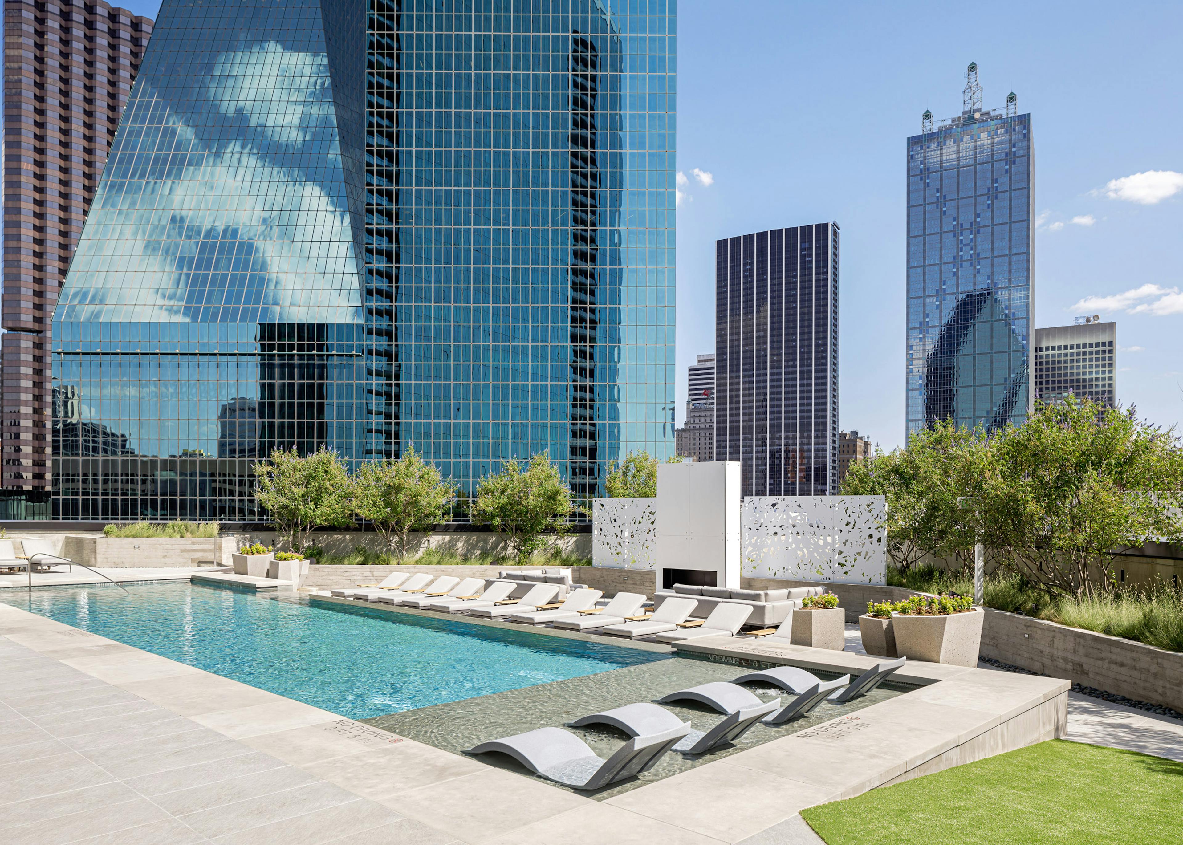 AMLI at Fountain Place landscaped rooftop swimming pool surrounded by lounge chairs on 3 sides and large office buildings