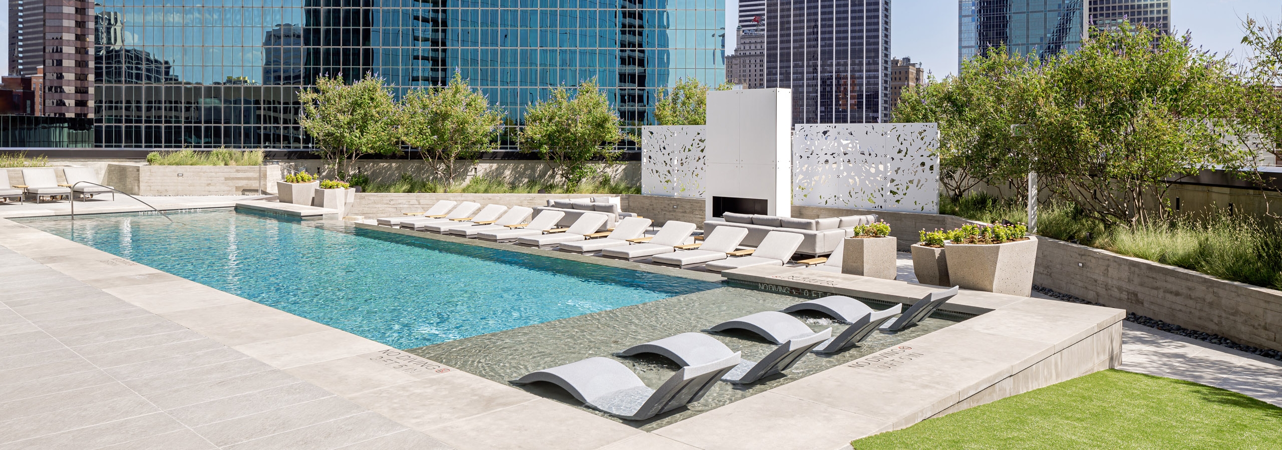AMLI at Fountain Place landscaped rooftop swimming pool surrounded by lounge chairs on 3 sides and large office buildings